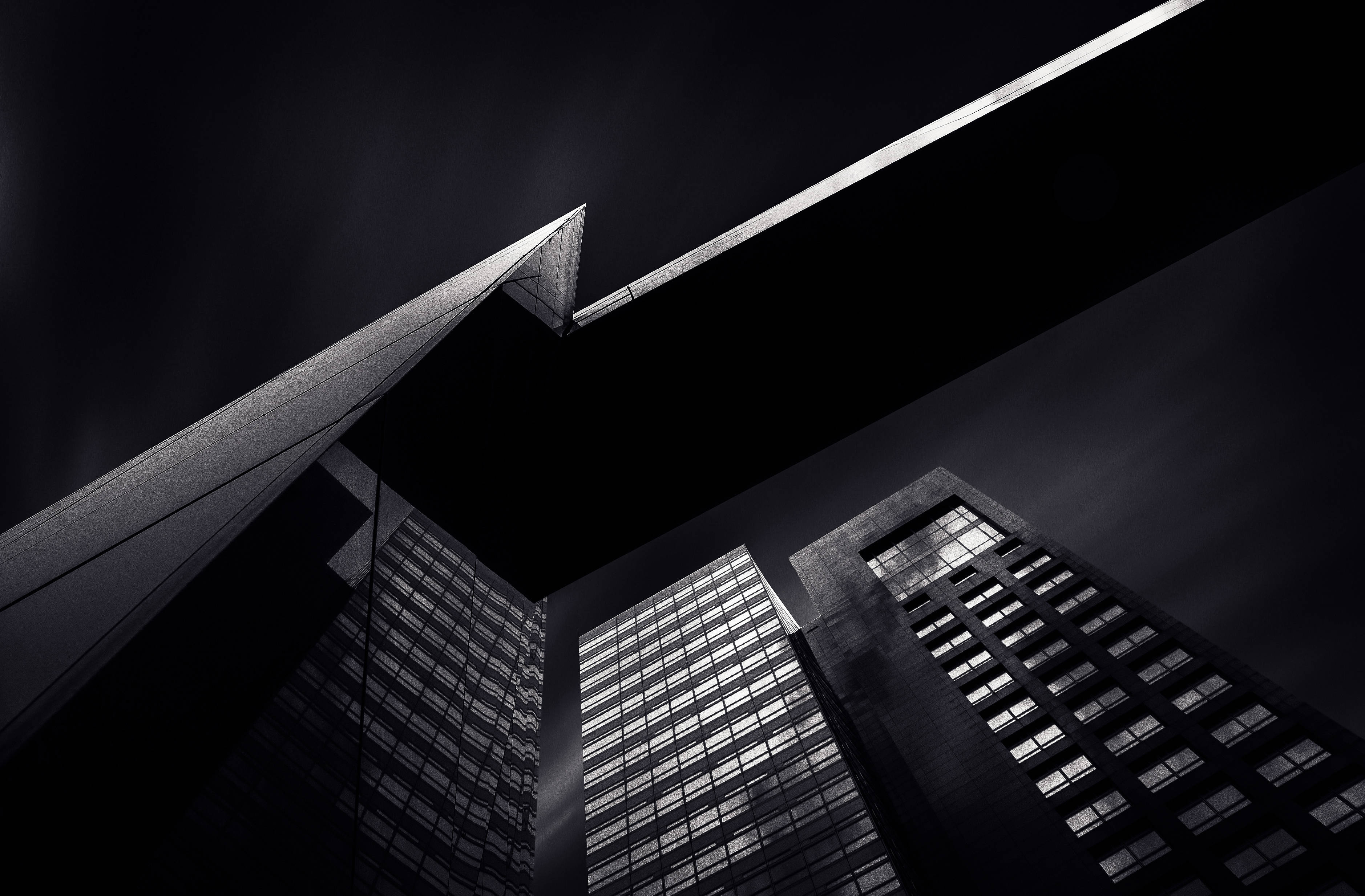 City Art 桌布 壁紙 — 低角度黑白拍攝，摩天大樓高聳入雲，窗戶燈火通明，戲劇性十足。