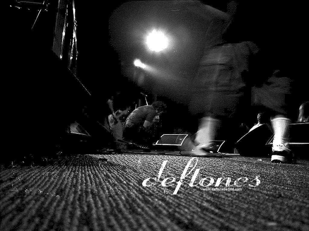 deftones 桌布 壁紙 — 低角度黑白照片捕捉到一位模糊的音樂家在現場音樂會中於明亮舞台燈光下表演。