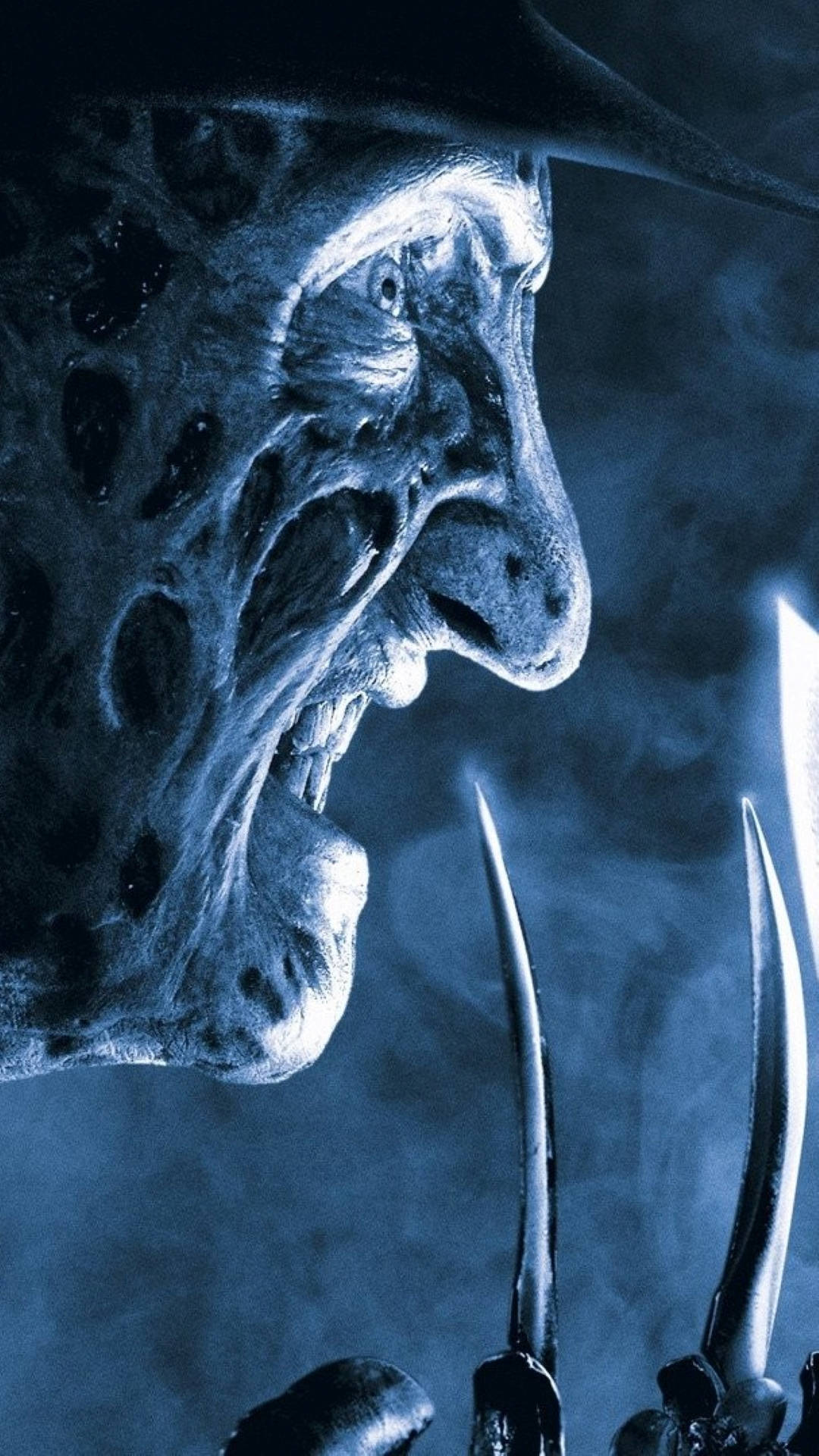 Freddy 桌布 壁紙 — 佛萊迪·克魯格傷痕累累的臉和刀片手套在詭異藍色煙霧中的令人毛骨悚然的特寫。