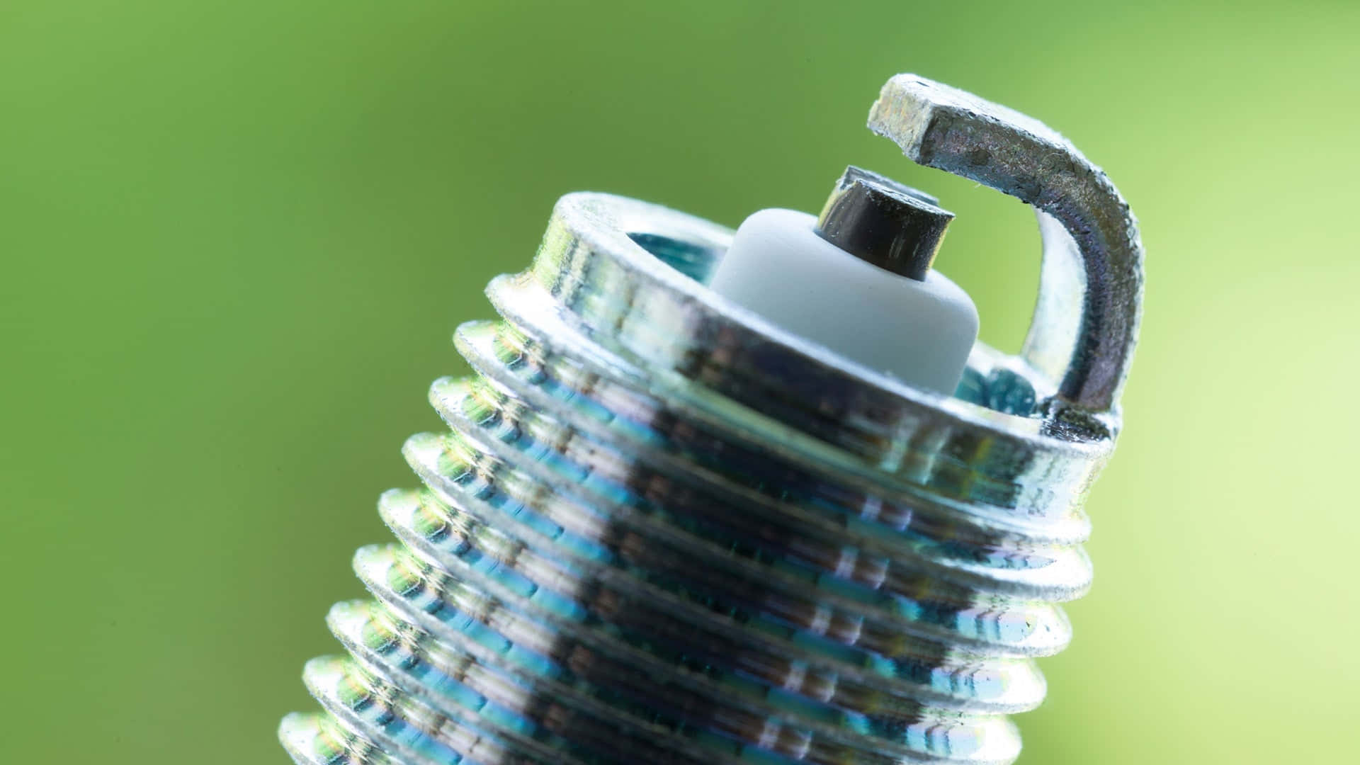 Spark Plug 桌布 壁紙 — 使用過的火星塞特寫，電極磨損，背景為柔和綠色。