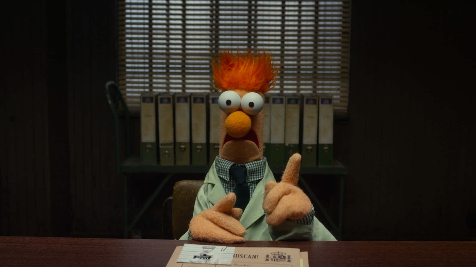 Animal Muppet 桌布 壁紙 — 來自《布偶家族》的Beaker坐在昏暗辦公室的書桌前，興奮地指著文件，表情驚訝。