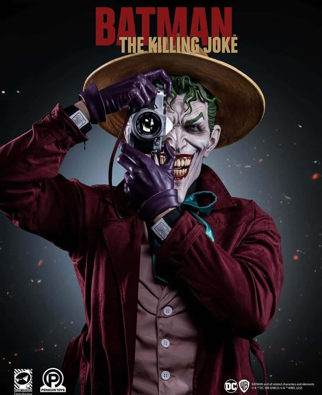 Batman The Killing Joke 桌布 壁紙 — 來自《蝙蝠俠：致命玩笑》的小丑，在黑暗背景中浮動的火花襯托下，將相機舉到臉前，露出陰險的笑容。