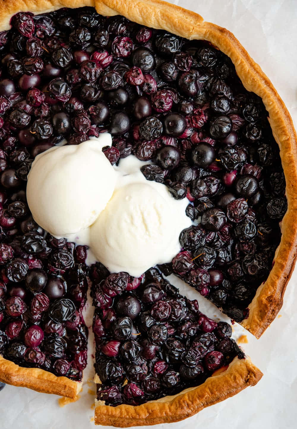 Blueberries Tart 桌布 壁紙 — 俯拍鏡頭下，一個金黃色的藍莓派，上面有兩球正在融化的香草冰淇淋。
