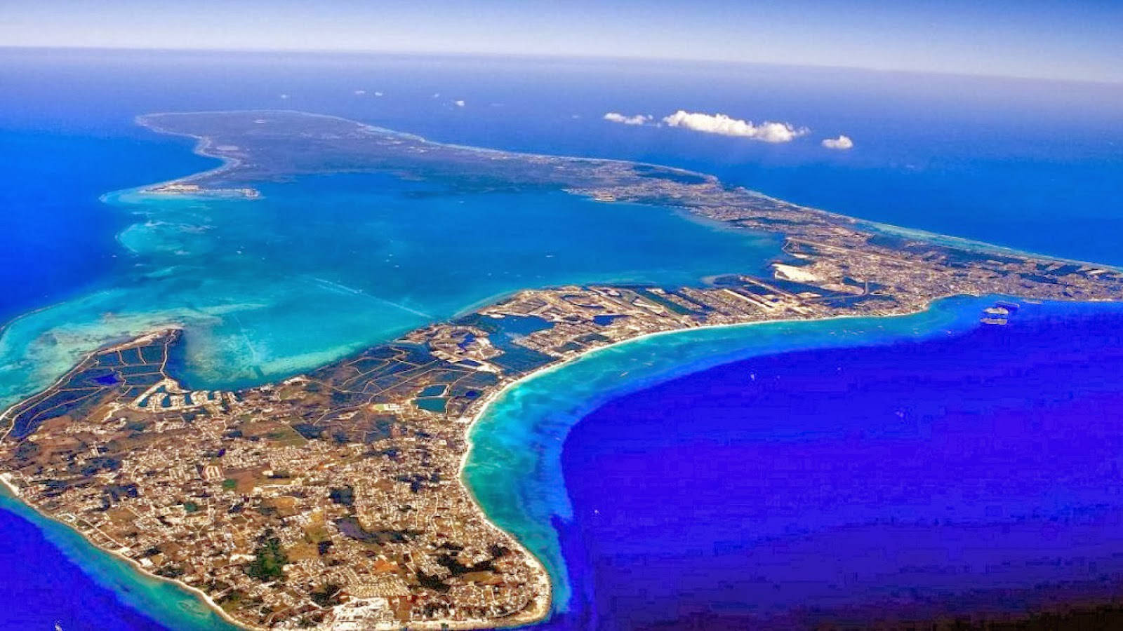 Cayman 桌布 壁紙 — 俯瞰一個充滿活力的沿海島嶼，碧綠海水與城市擴張在深藍色海洋的映襯下。
