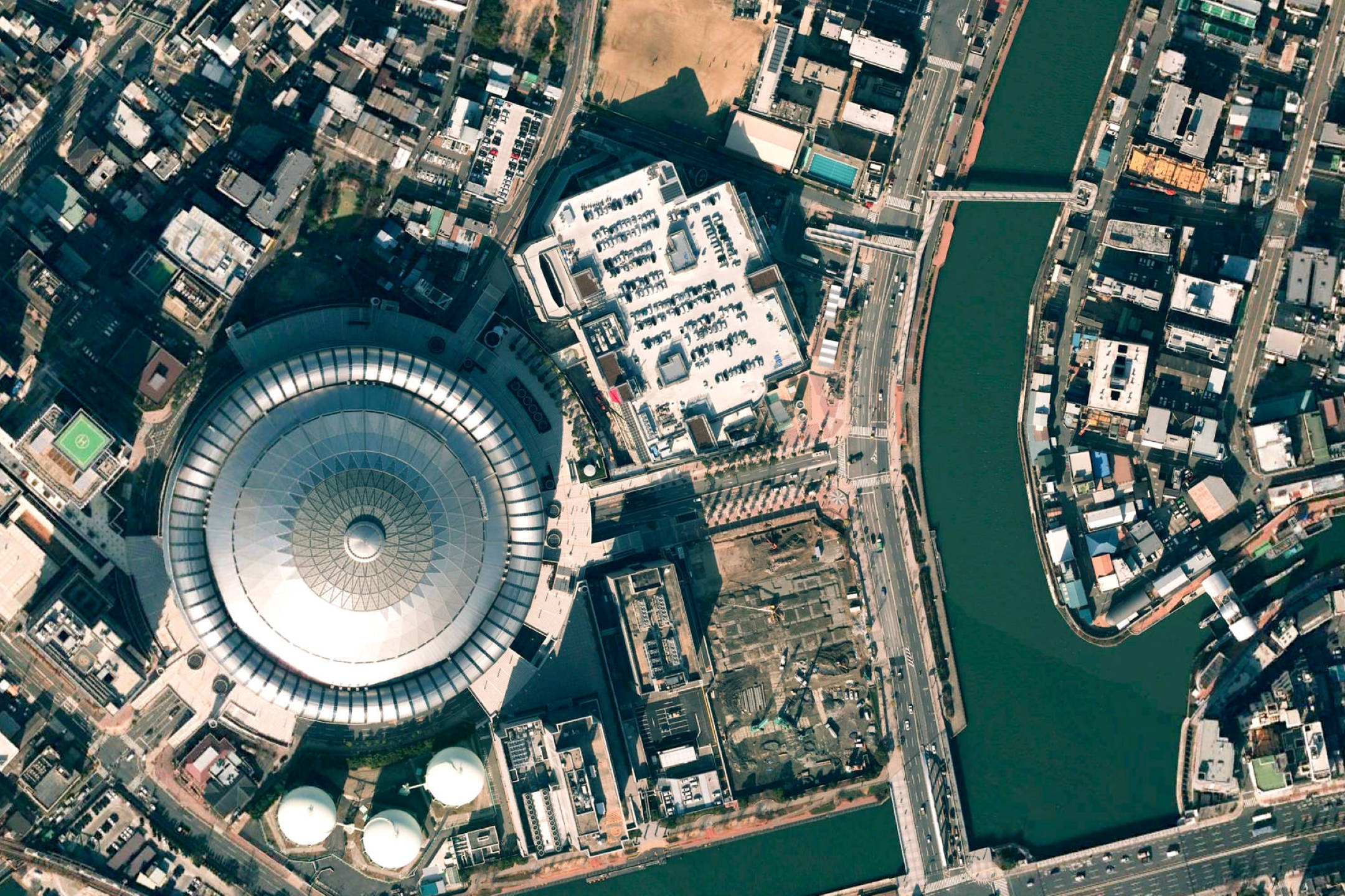 Google 地球 桌布 壁紙 — 俯瞰一個大型圓頂體育館，坐落於城市建築物和蜿蜒河流之間。