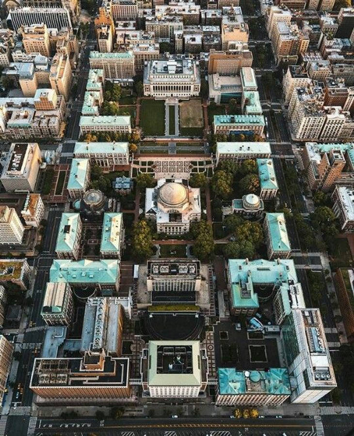 建築 桌布 壁紙 — 俯瞰一個宏偉的大學校園，擁有圓頂建築和綠色草坪，周圍環繞著城市摩天大樓。