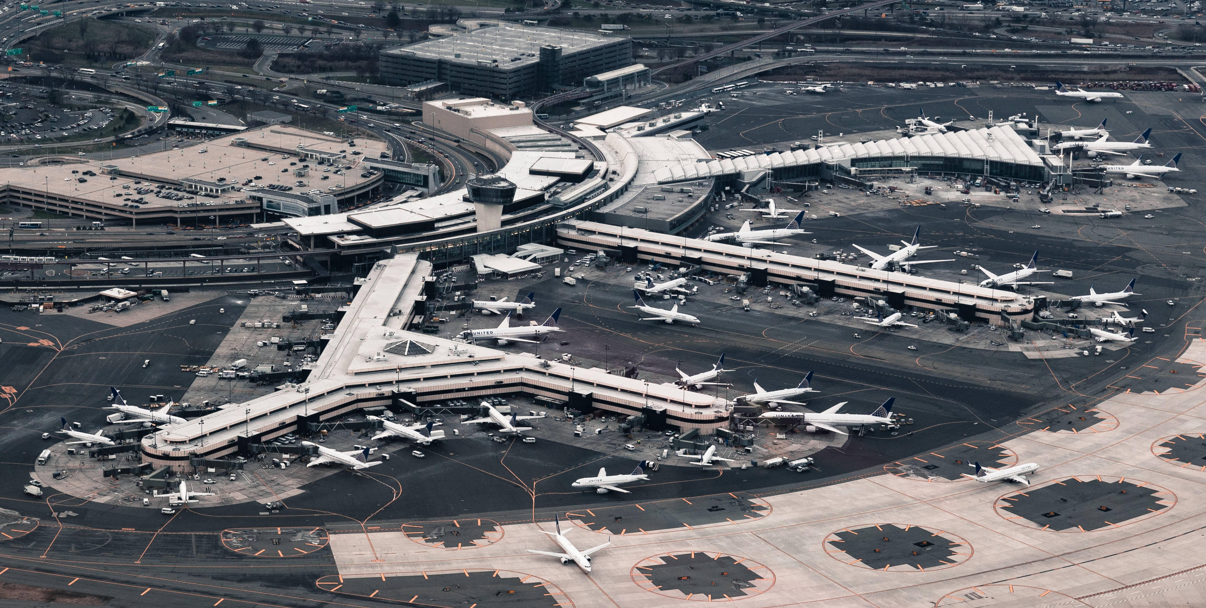 Airport 桌布 壁紙 — 俯瞰一個廣闊的現代化機場，眾多飛機停泊在彎曲的登機橋和滑行道上。