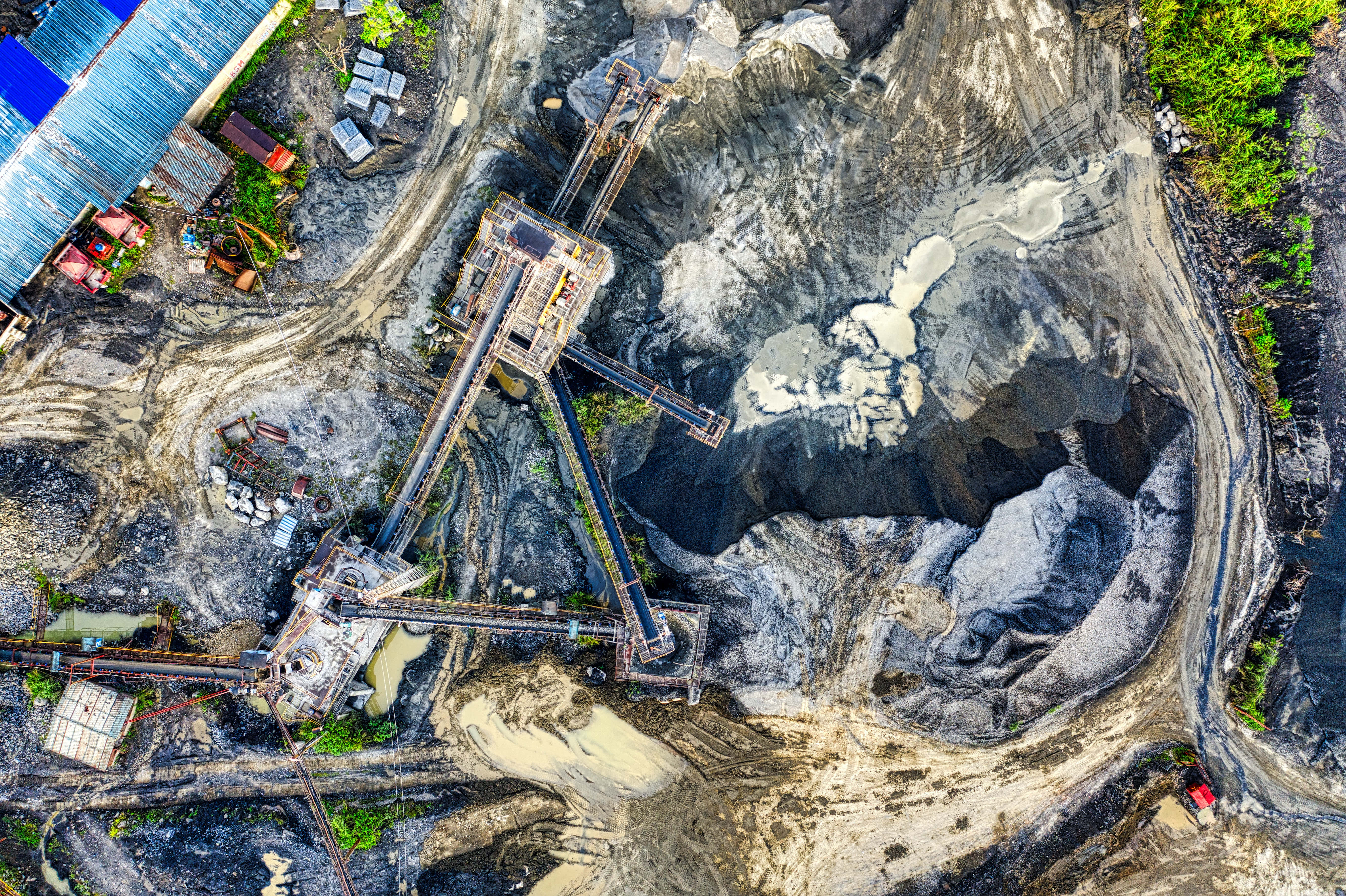 Mining 桌布 壁紙 — 俯瞰一個廣闊的露天礦場，輸送帶在崎嶇地形上運送深色礦石。