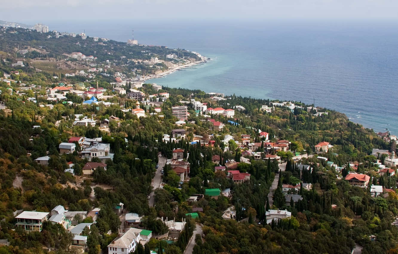 Town 桌布 壁紙 — 俯瞰一個沿海小鎮，坐落在鬱鬱蔥蔥的綠色山丘之間，碧綠的海水與海岸相接。