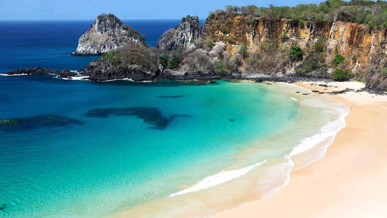 Brazilian Beach 桌布 壁紙 — 俯瞰一個隱蔽的熱帶小海灣，碧綠的海水拍打著金色沙灘，兩側是崎嶇的懸崖。