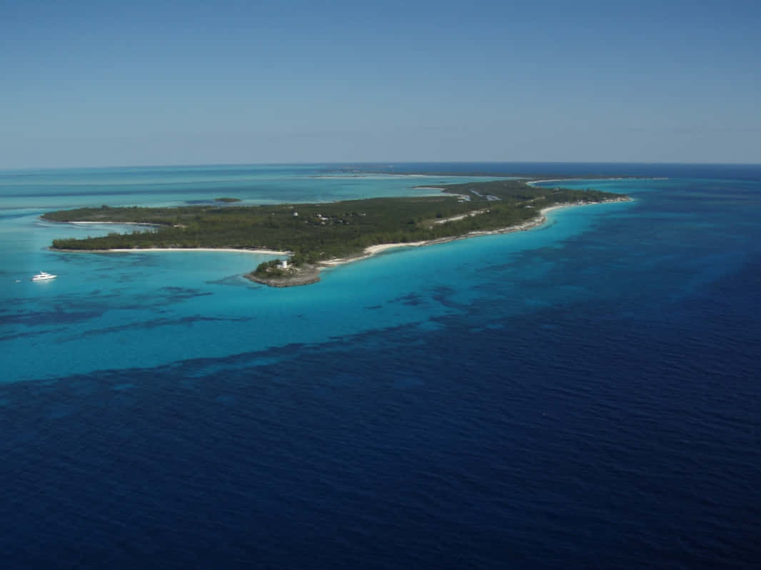 Bahamas Island 桌布 壁紙 — 俯瞰一個鬱鬱蔥蔥的熱帶島嶼，周圍環繞著碧綠色的潟湖和深藍色的海洋。