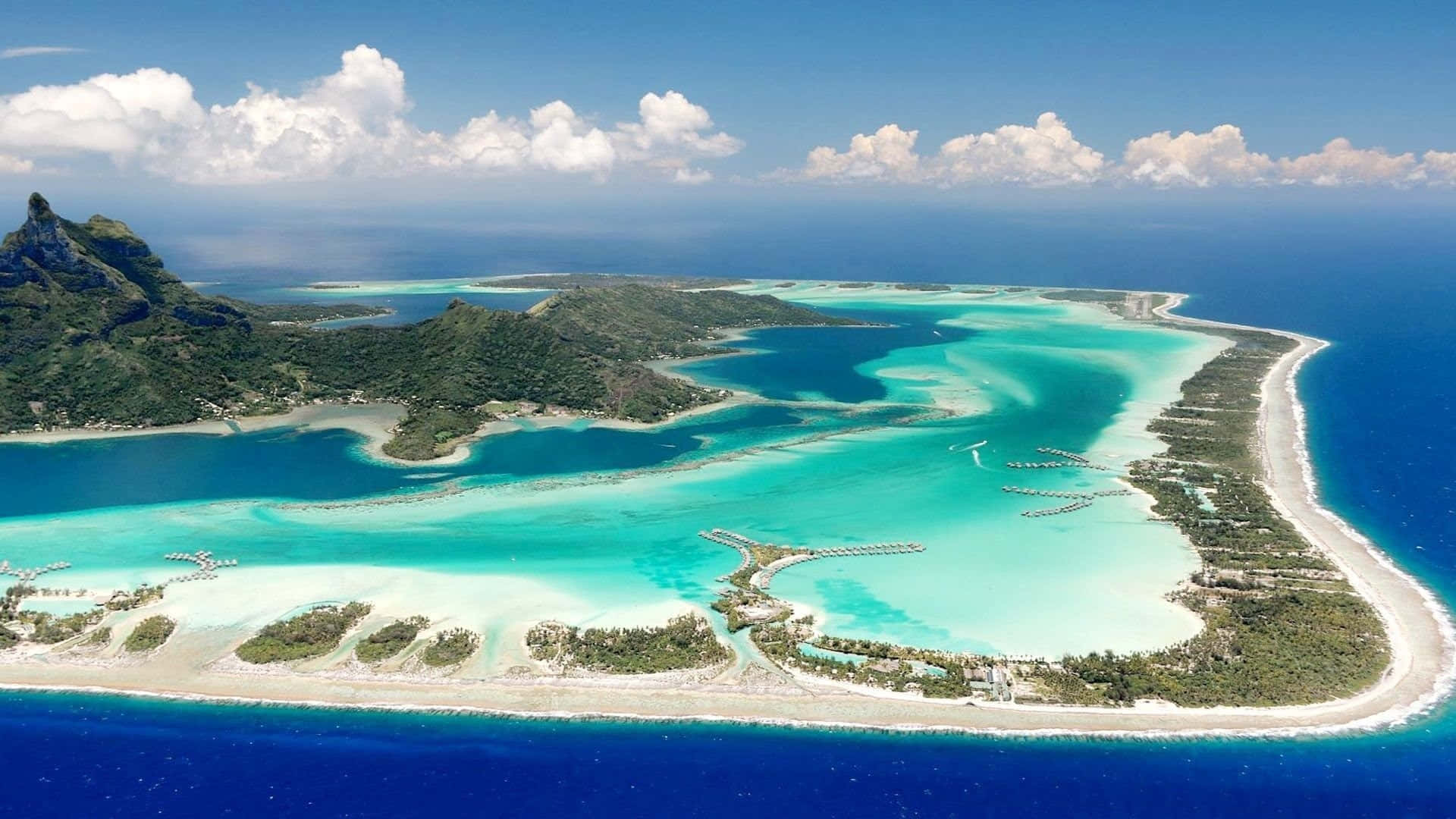 Bora Bora 桌布 壁紙 — 俯瞰一個鬱鬱蔥蔥的熱帶島嶼，擁有碧綠色的潟湖、珊瑚礁和白色沙灘，四周環繞著深藍色的海洋。