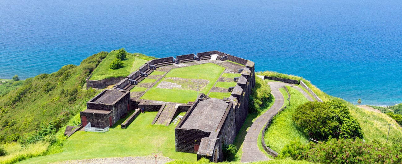 島嶼 桌布 壁紙 — 俯瞰一座歷史悠久的石頭堡壘，坐落在鬱鬱蔥蔥的綠色懸崖上，俯瞰著充滿活力的藍色海水。