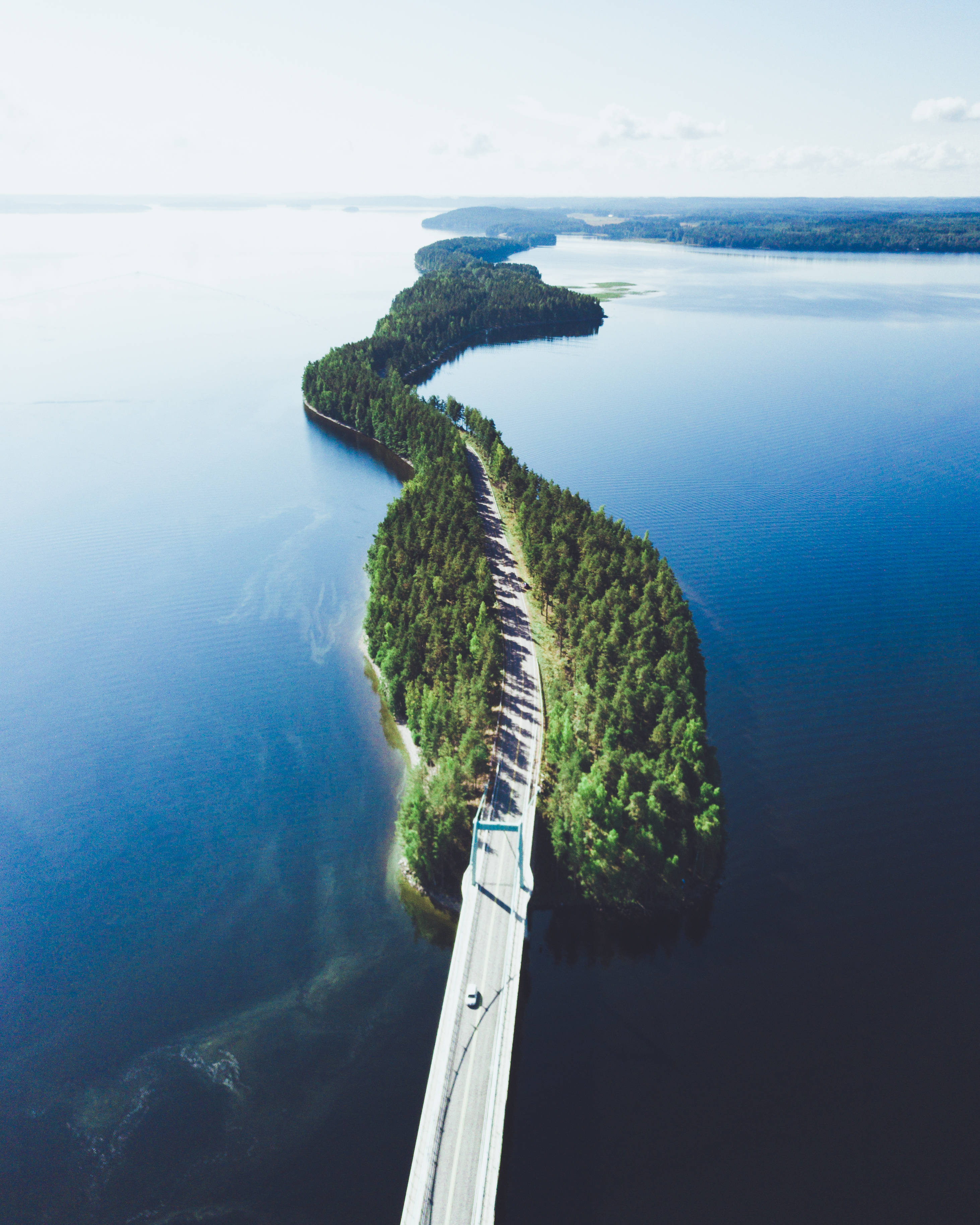 Finland 桌布 壁紙 — 俯瞰一條蜿蜒的公路橋橫跨深藍色水域，下方是鬱鬱蔥蔥的森林島嶼。