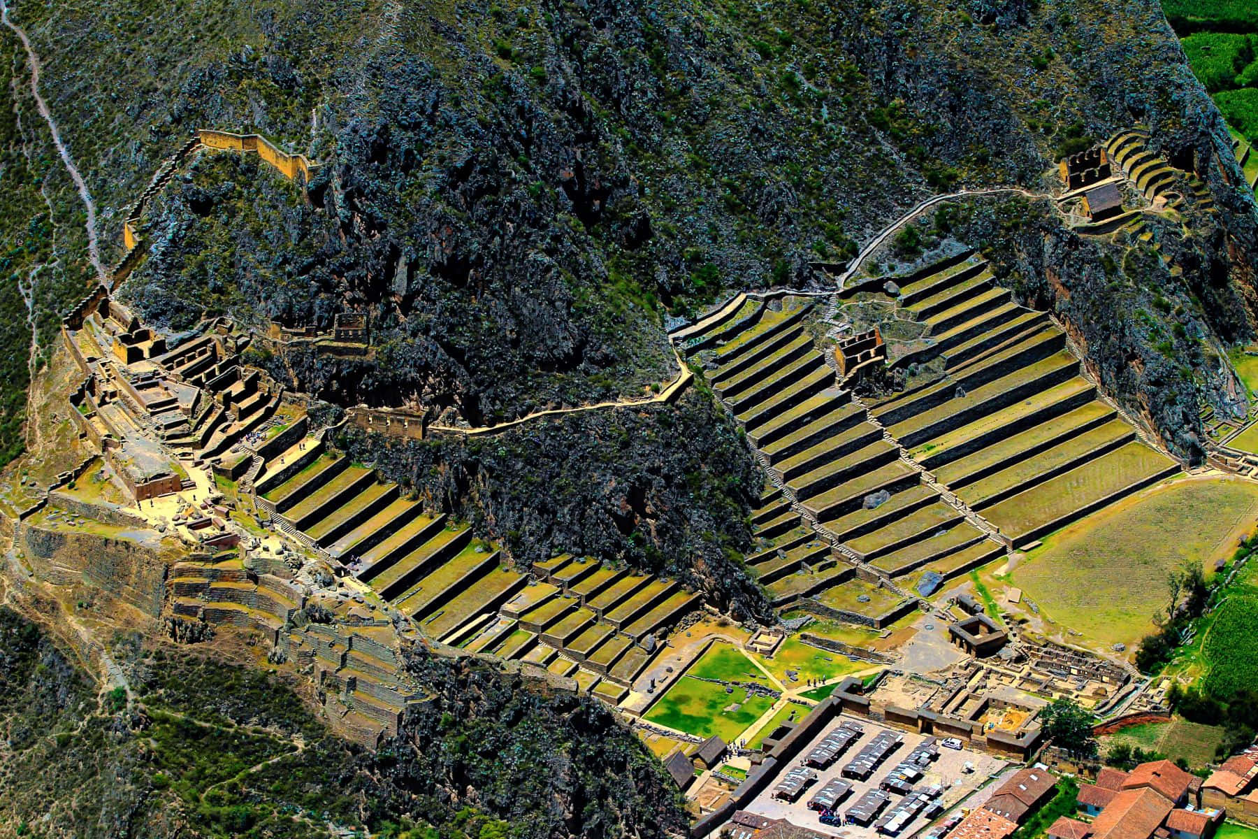Valley 桌布 壁紙 — 俯瞰古老印加梯田和石結構，雕刻在陡峭的山坡上，周圍綠意盎然。