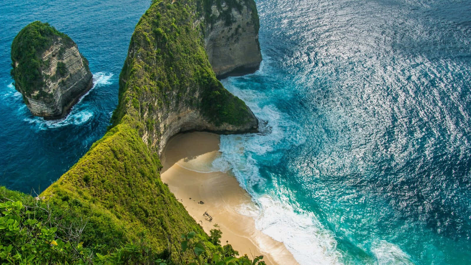 Cliff 桌布 壁紙 — 俯瞰圖：一片隱藏在翠綠懸崖與拍岸海浪之間的寧靜碧綠海灘。