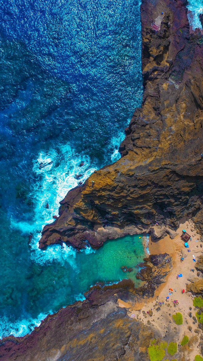 俯瞰圖：一個僻靜沙灘，碧綠海水和崎嶇懸崖。 — Google pixel 壁紙