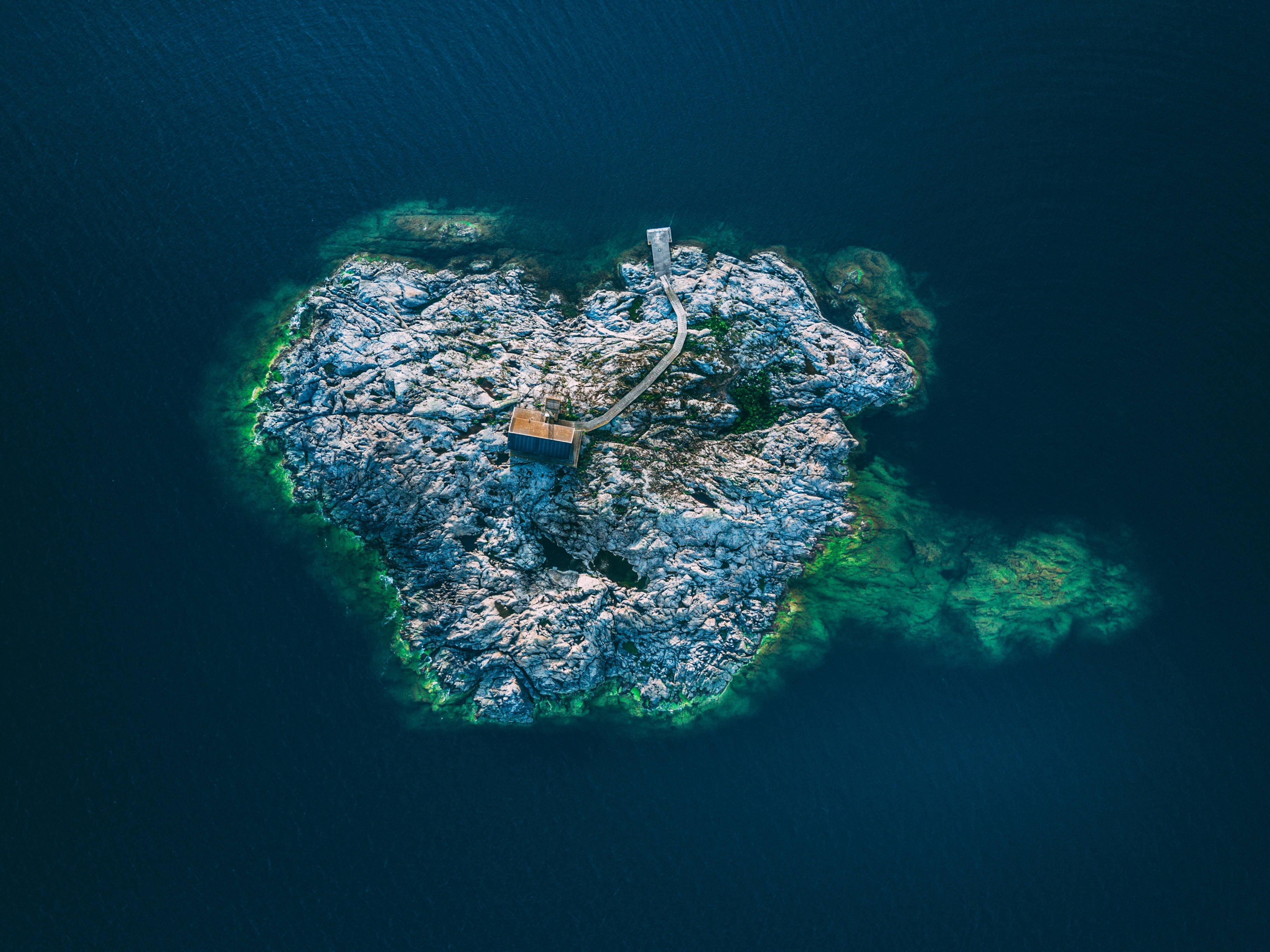 Sweden 桌布 壁紙 — 俯瞰心形岩石島嶼，島上有木屋和碼頭，周圍是深藍色海水。