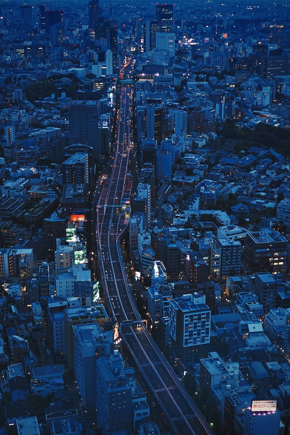 日本 桌布 壁紙 — 俯瞰暮色中燈火通明的街道與建築，城市在深藍色暮光下延伸。