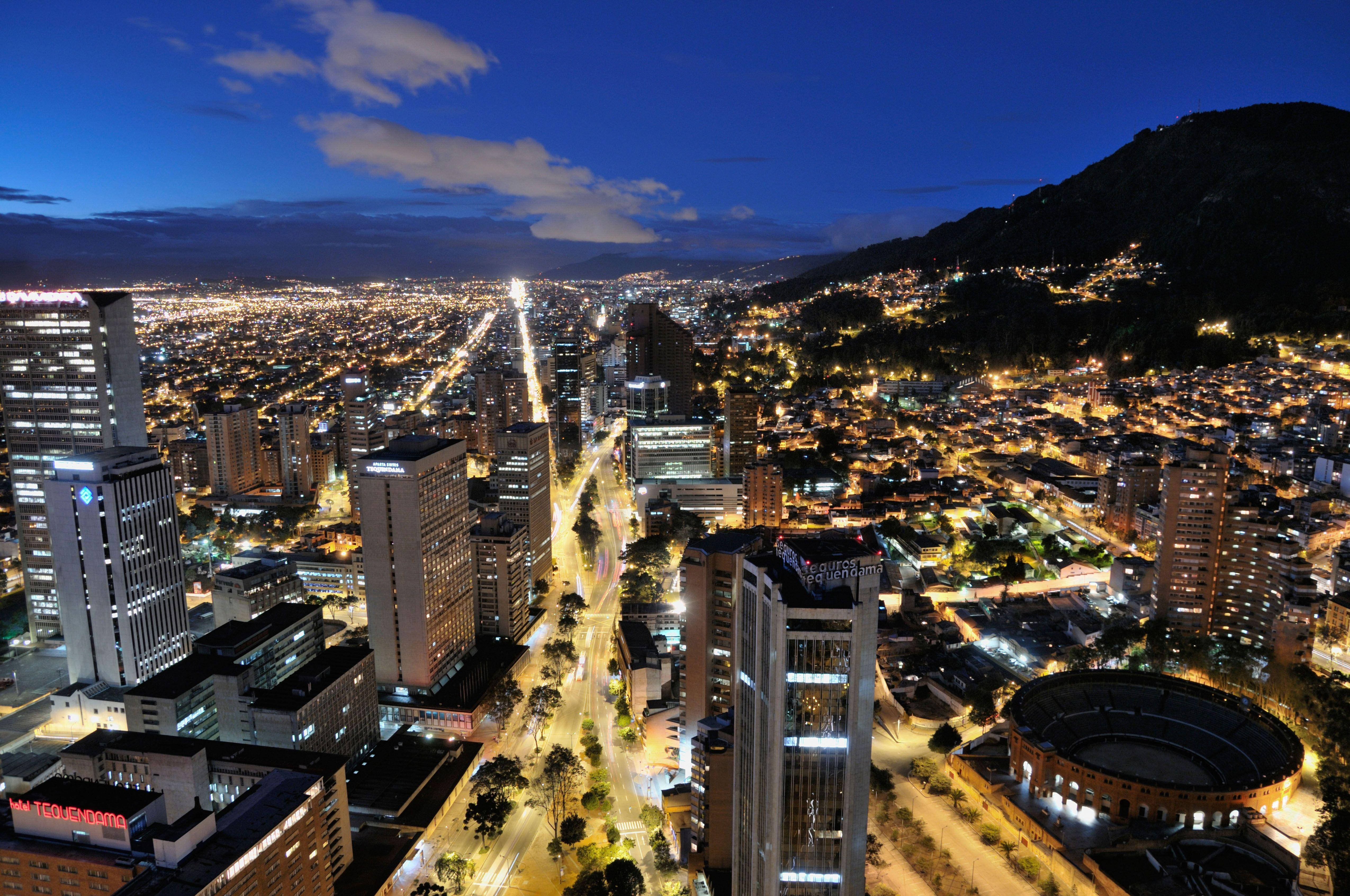 Bogota 桌布 壁紙 — 俯瞰暮色中蔓延的城市，發光的街道和建築物依偎在黑暗的山坡上。