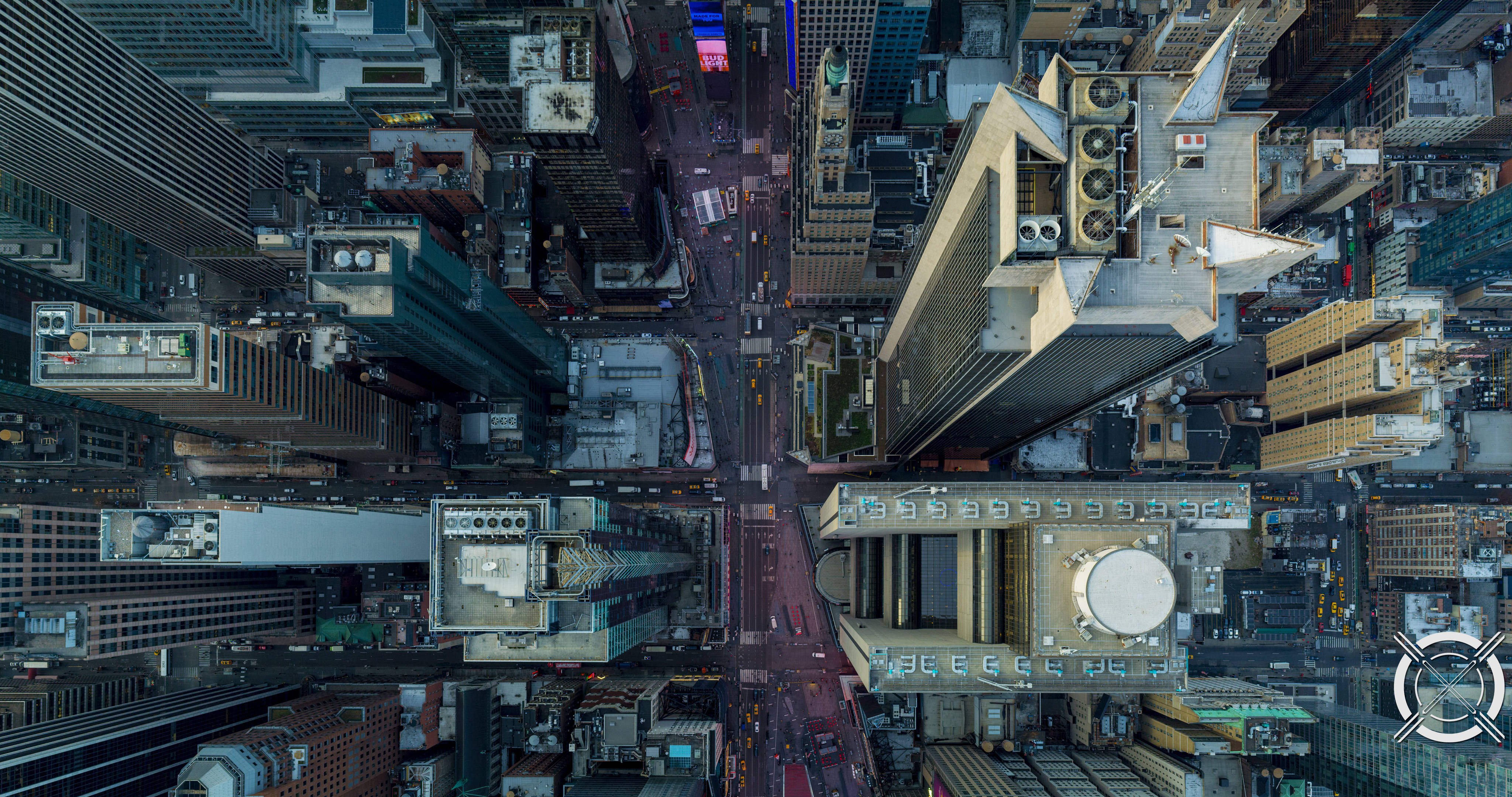 Buildings 桌布 壁紙 — 俯瞰繁華城市街道的航拍視圖，兩旁是高聳的摩天大樓，閃爍著霓虹燈招牌。