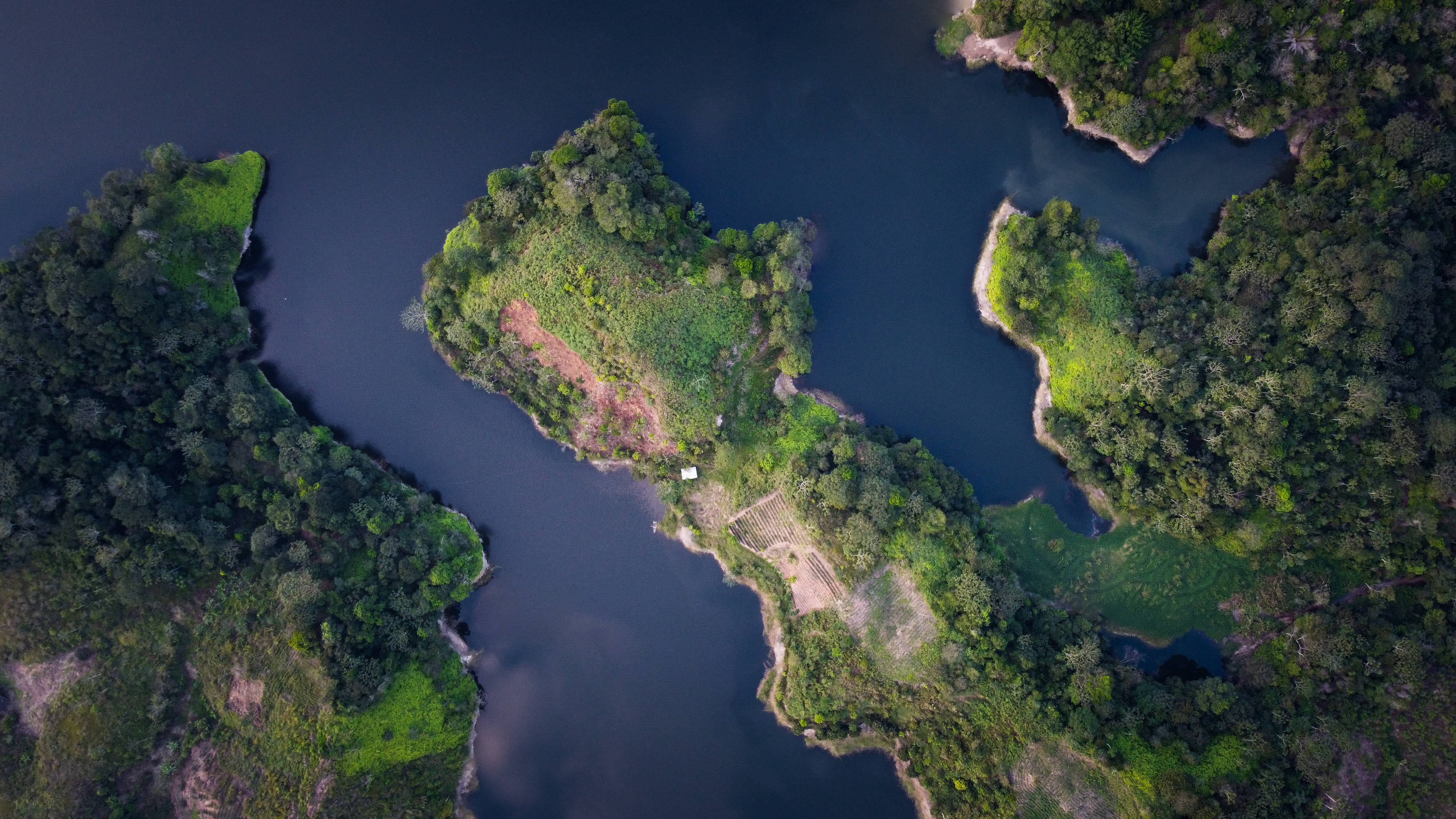 Honduras 桌布 壁紙 — 俯瞰茂密綠色島嶼被深藍色海水包圍，其中一個島嶼上可見人類建築。