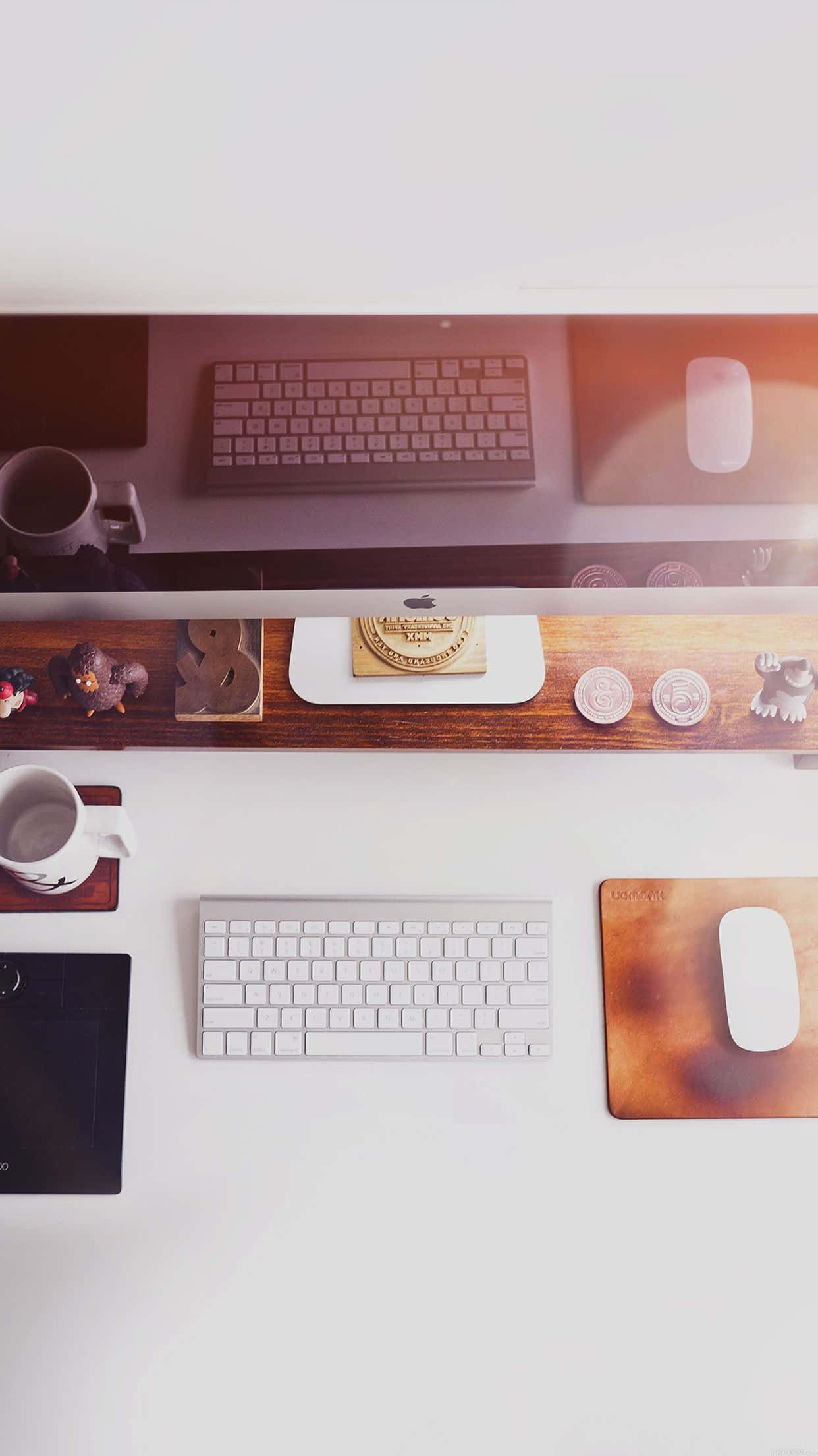 Best Office 桌布 壁紙 — 俯瞰視角，一張簡約白色書桌，上面有兩個鍵盤、滑鼠墊和咖啡杯，在溫暖的環境光下。