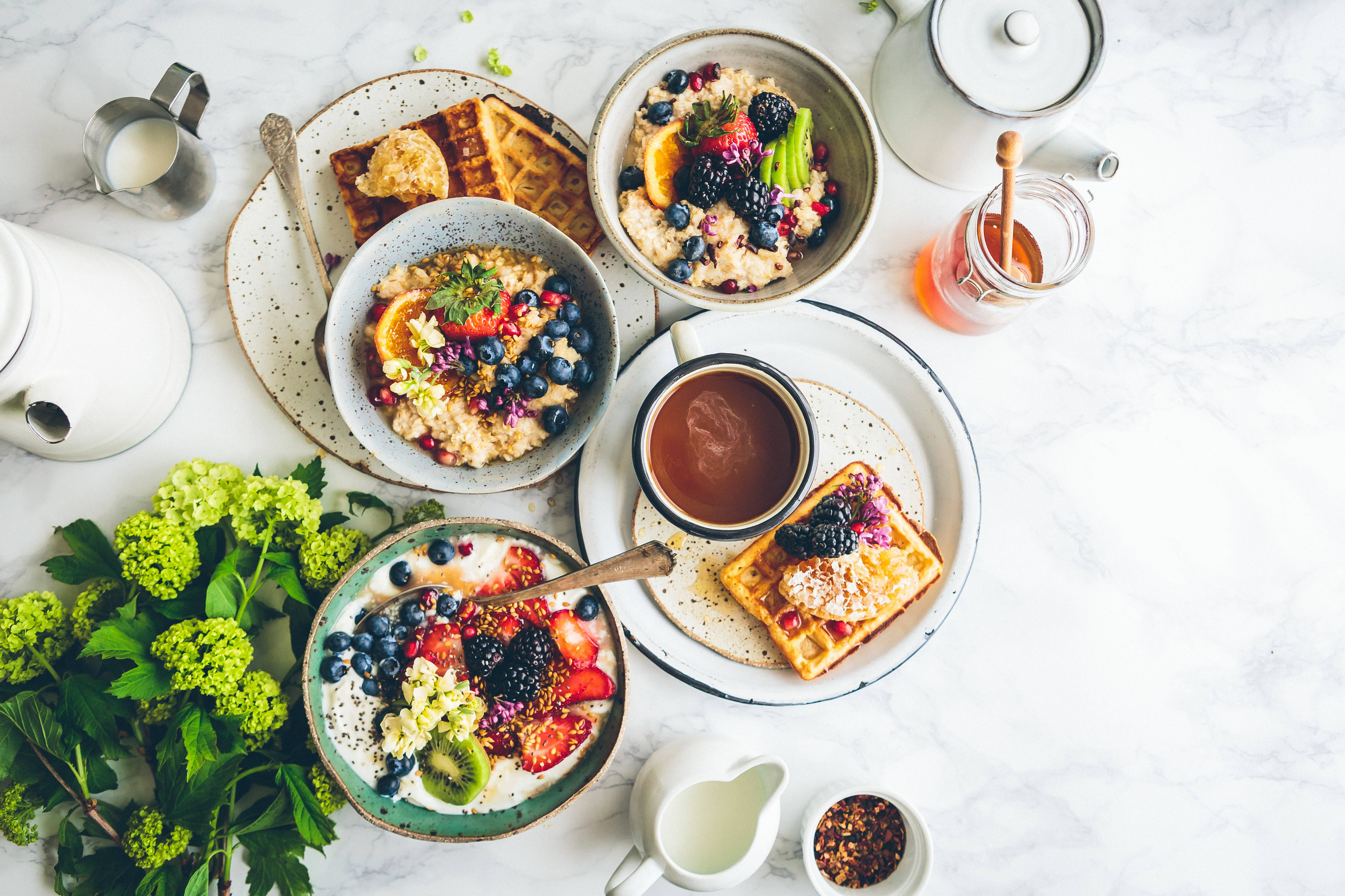 Waffle 桌布 壁紙 — 俯瞰視角，白色大理石表面上擺放著一碗碗燕麥片、漿果、鬆餅和咖啡，色彩繽紛的早餐拼盤。