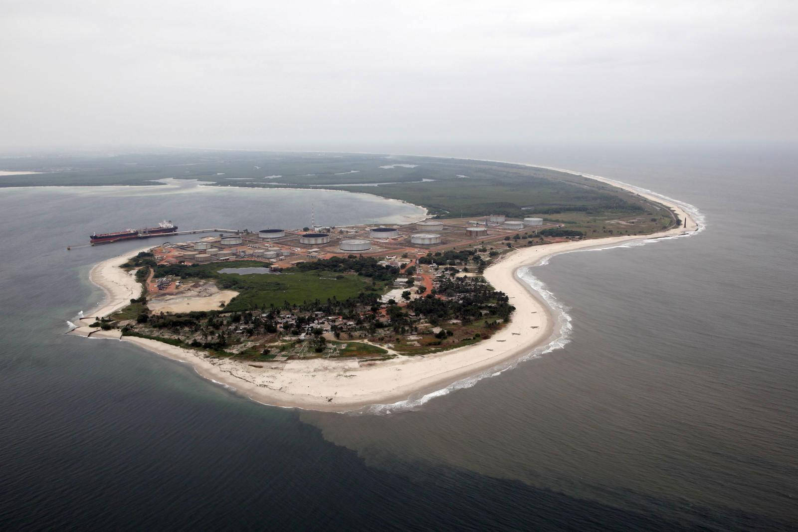水 桌布 壁紙 — 俯瞰視角下的沿海島嶼，設有工業儲存罐，附近有一艘貨船在陰天停泊。