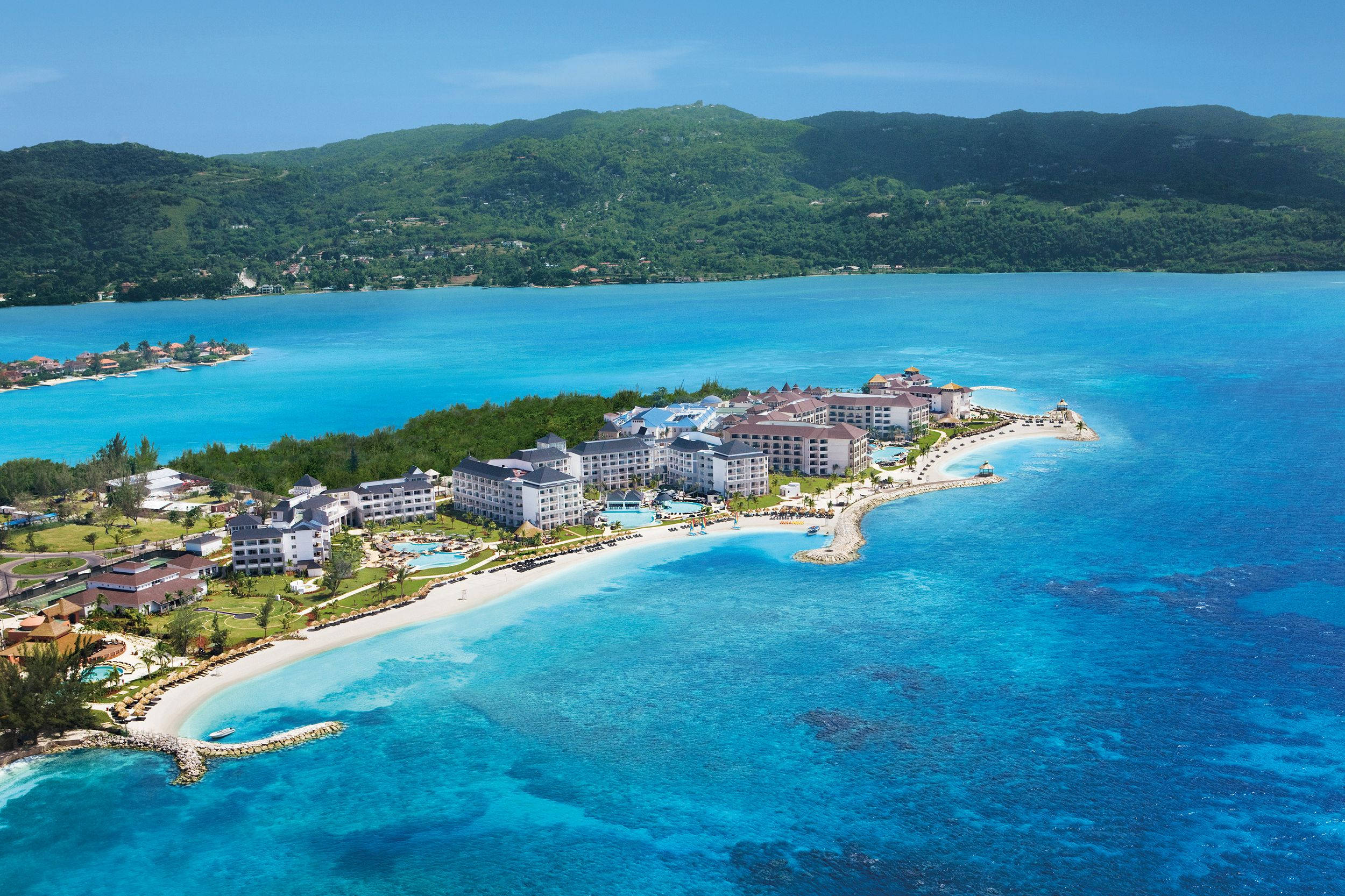 Jamaica 桌布 壁紙 — 俯瞰豪華度假村坐落在白色沙灘上，背景是碧綠的海水和鬱鬱蔥蔥的綠色山丘。