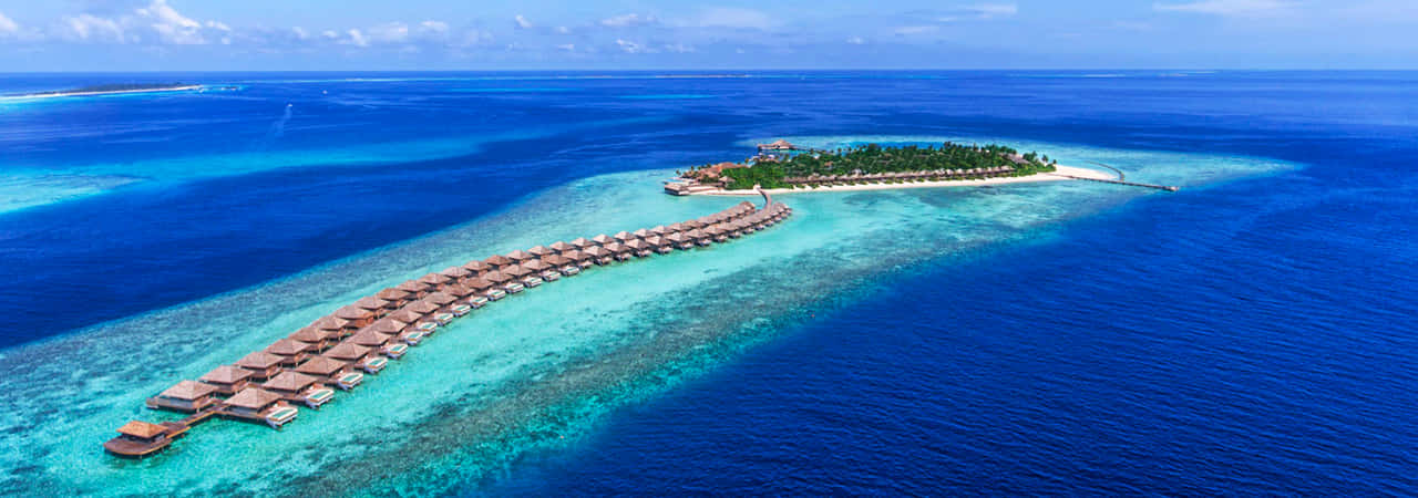 Maldives Island 桌布 壁紙 — 俯瞰豪華水上平房度假村，橫跨碧綠潟湖水域，延伸至鬱鬱蔥蔥的綠色島嶼。