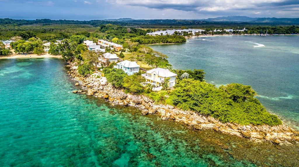 Jamaican Island 桌布 壁紙 — 俯瞰豪華海灘別墅，坐落在鬱鬱蔥蔥的綠色島嶼上，擁有碧綠的海水和岩石海岸。