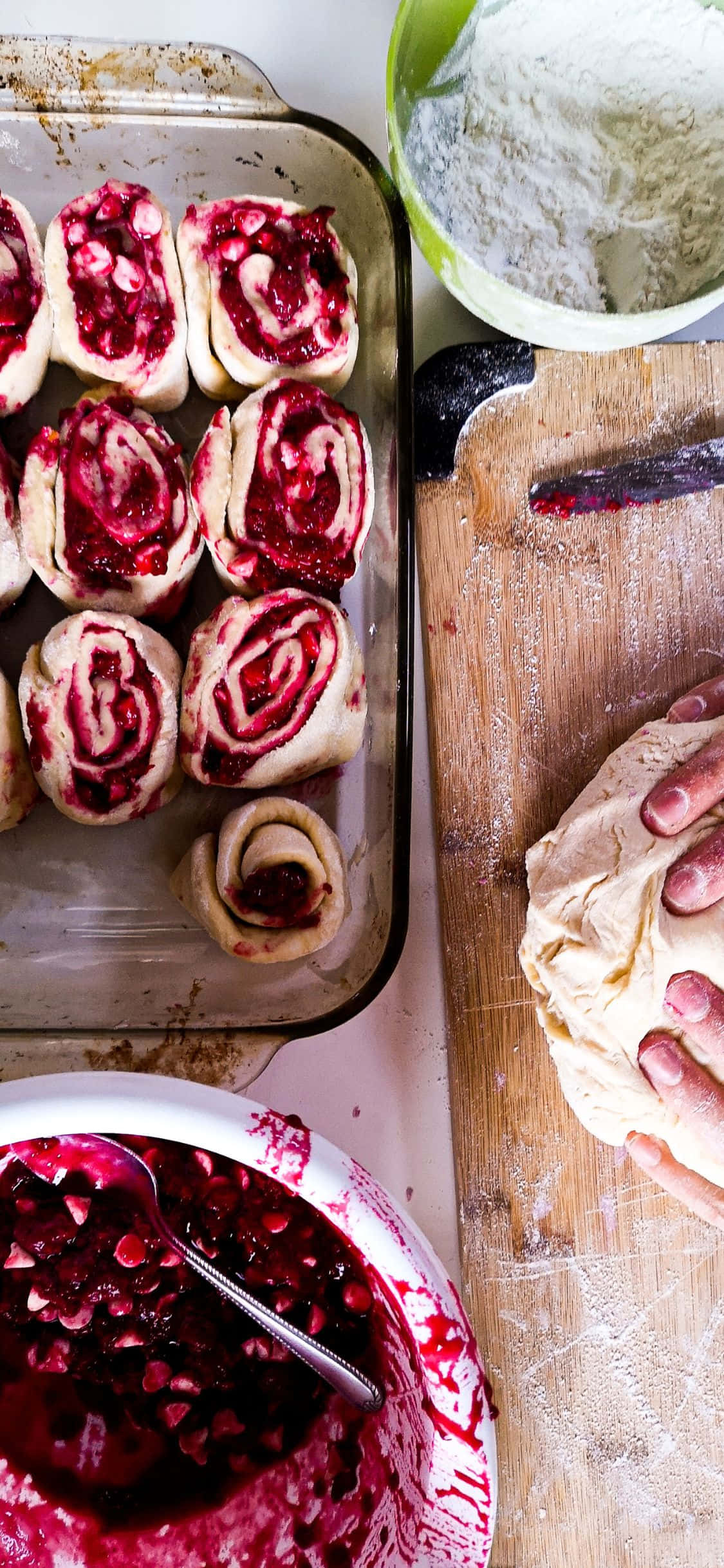 麵包 桌布 壁紙 — 俯瞰鏡頭：雙手在烤盤（內有覆盆子漩渦卷）及麵粉、果醬碗旁揉麵糰。