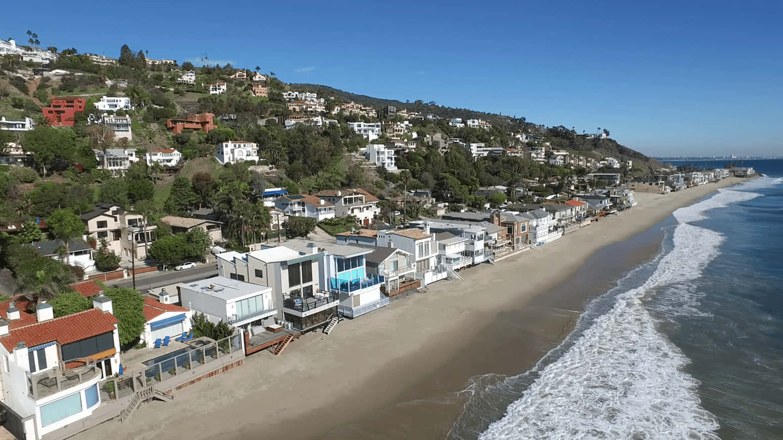 桌布 壁紙 — 俯瞰陽光普照的山坡上豪華海濱住宅，以及拍岸的海浪。