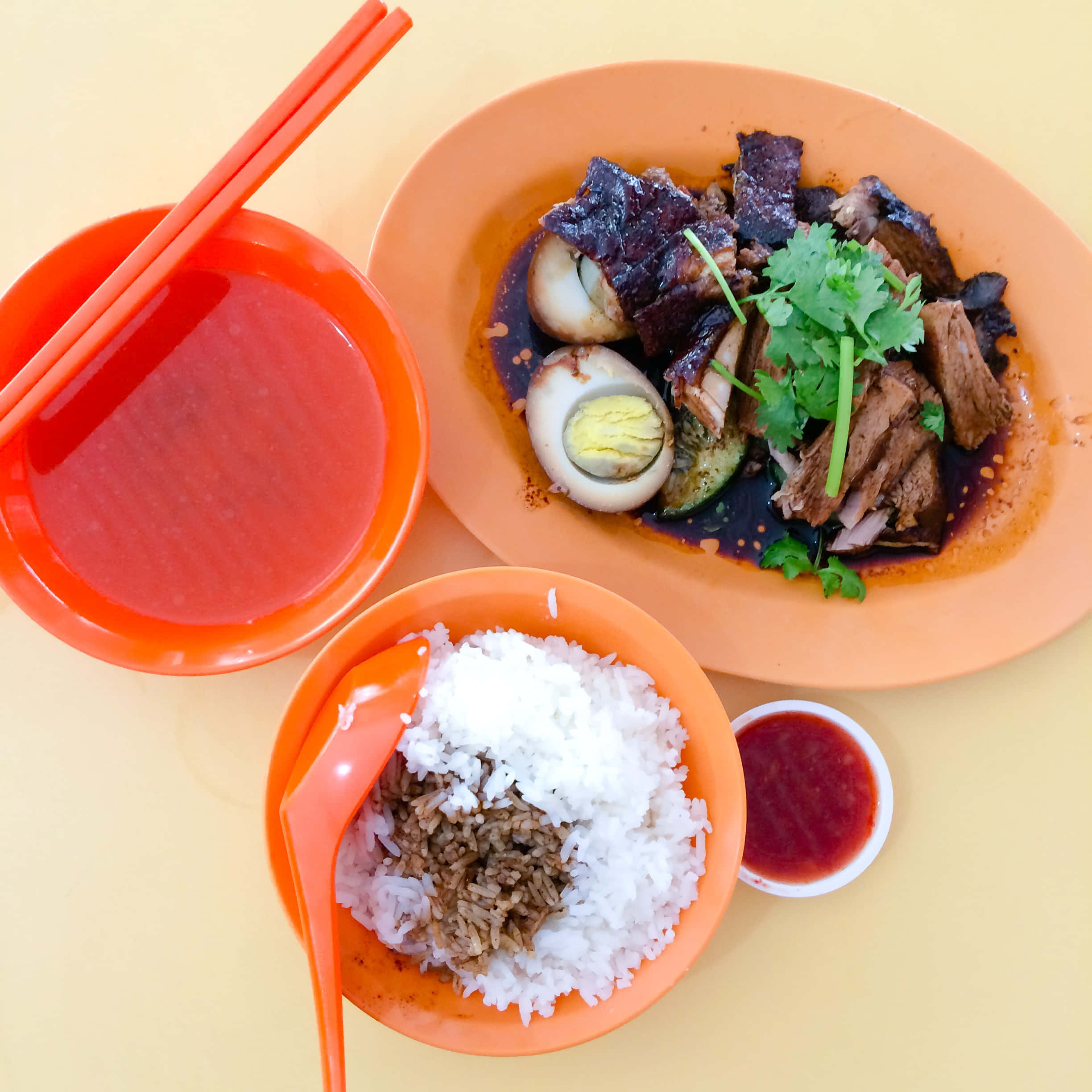 Food Photography 桌布 壁紙 — 俯視一個充滿活力的橙色盤子，上面有燉肉和香草，旁邊有碗飯和湯，還有筷子。