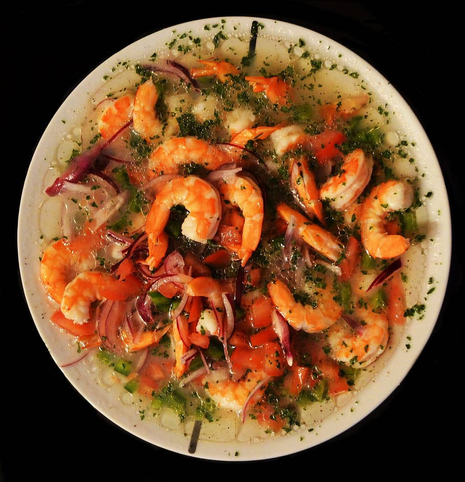 shrimp 桌布 壁紙 — 俯視圖，一個白色碗裝滿鮮豔的蝦肉酸橘汁醃魚，飾以紅洋蔥、綠色香草和番茄丁，背景為黑色。