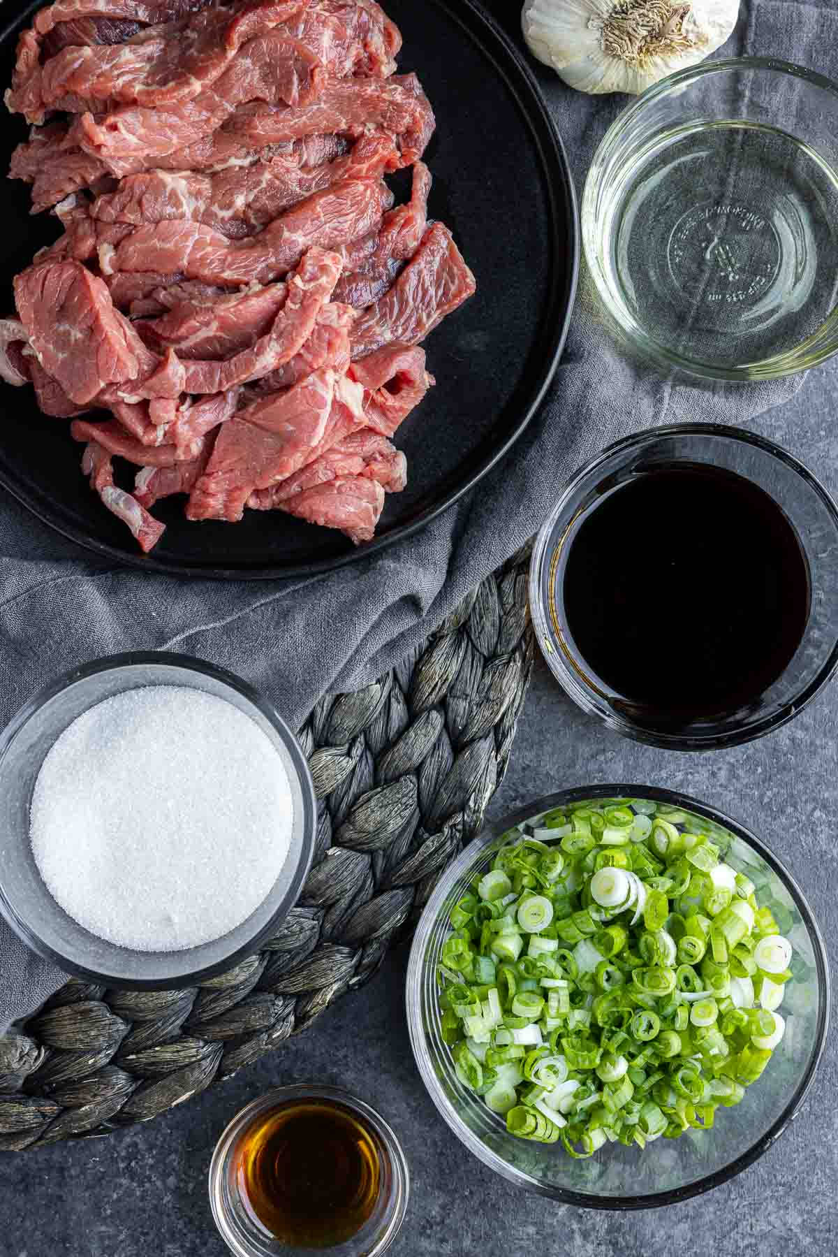 raw 桌布 壁紙 — 俯視圖：生牛肉條、糖、醬油、大蒜和切碎的青蔥排列在深色紋理表面上。