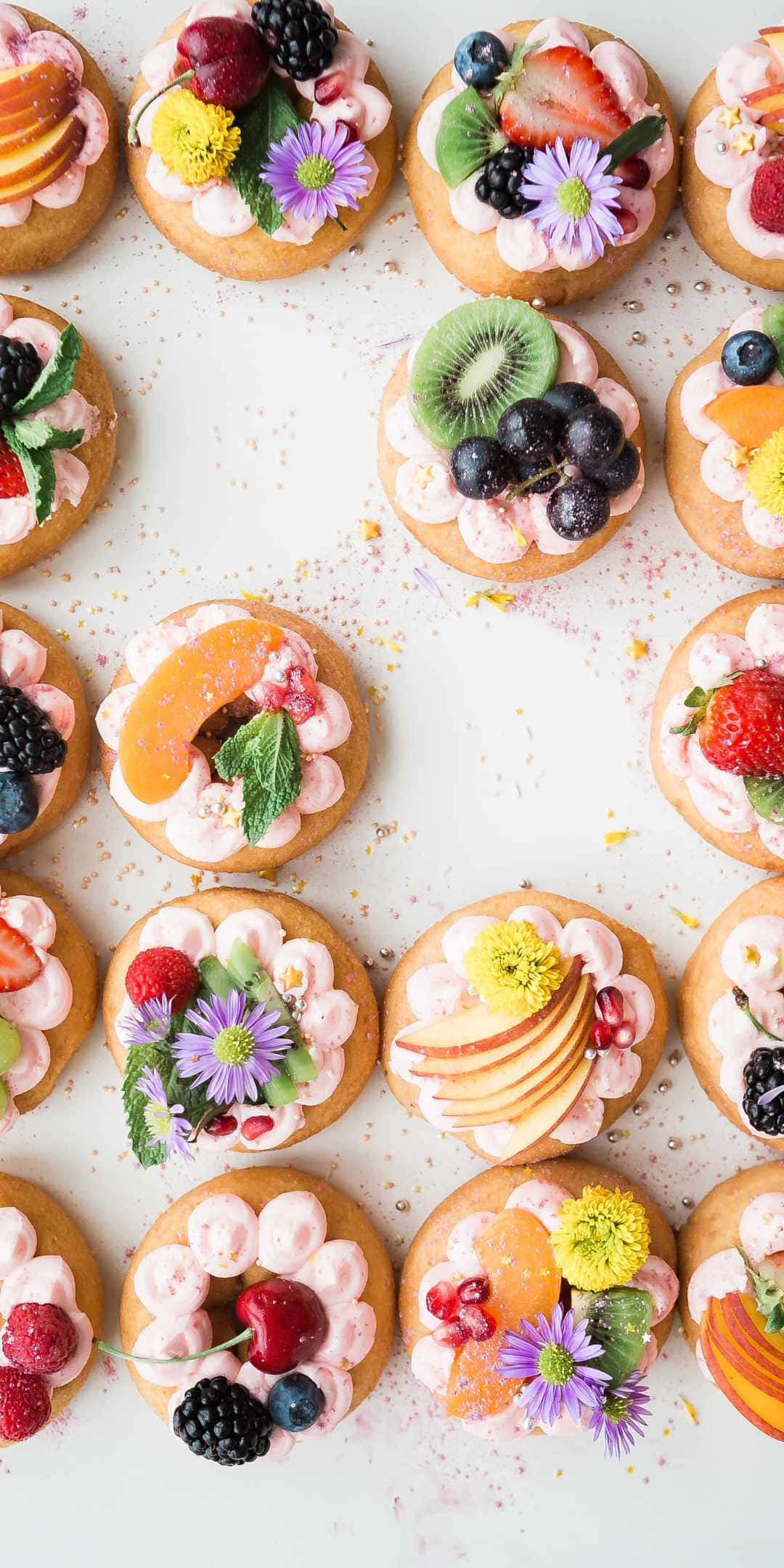 Pastry 桌布 壁紙 — 俯視圖，白色表面上色彩繽紛的迷你糕點，上面放有新鮮水果花和奶油。