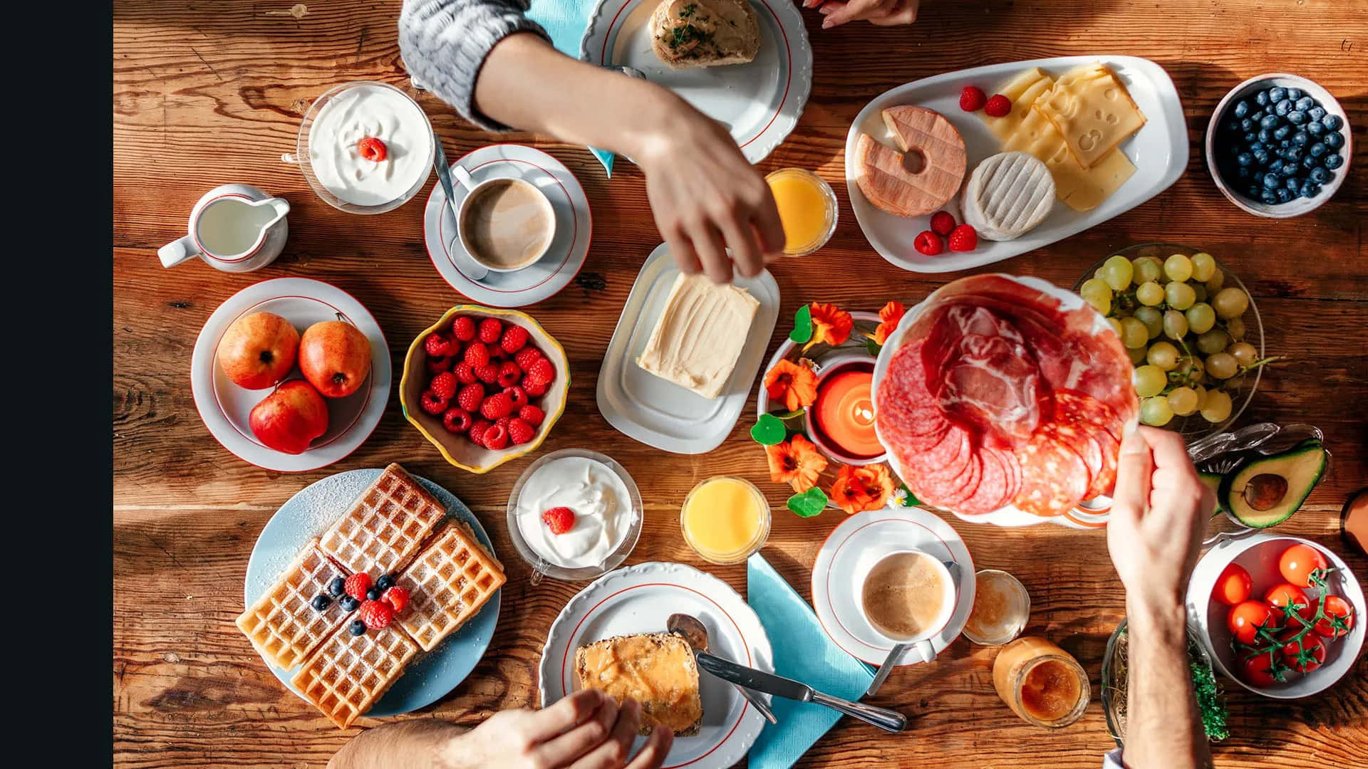 Brunch 桌布 壁紙 — 俯視角度拍攝雙手在鄉村風木桌上擺放豐盛早餐，有鬆餅、起司、水果和咖啡。
