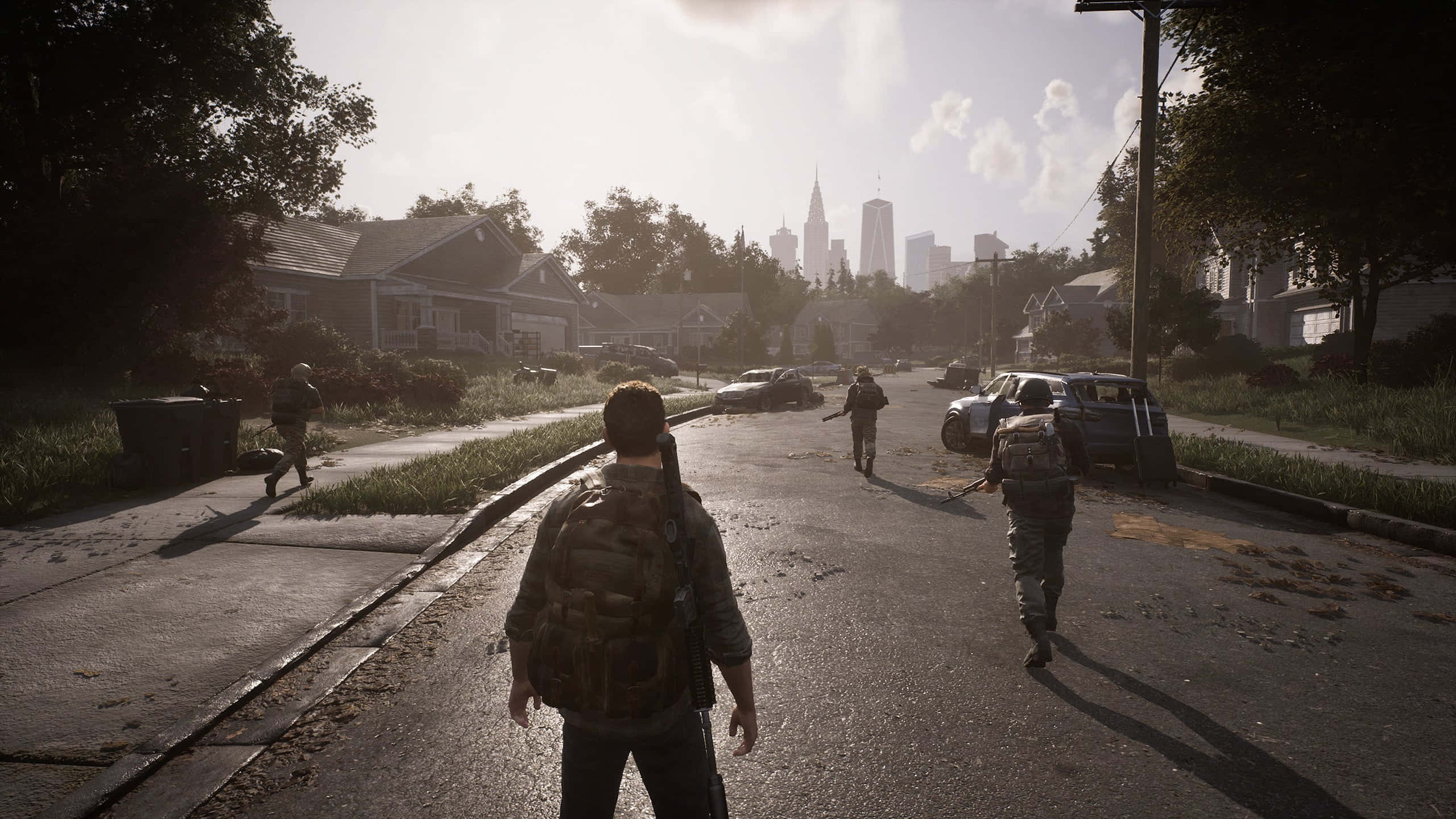 Game Trailers 桌布 壁紙 — 倖存者沿著陽光明媚的郊區街道，朝著朦朧天空下遠處的城市天際線前行。
