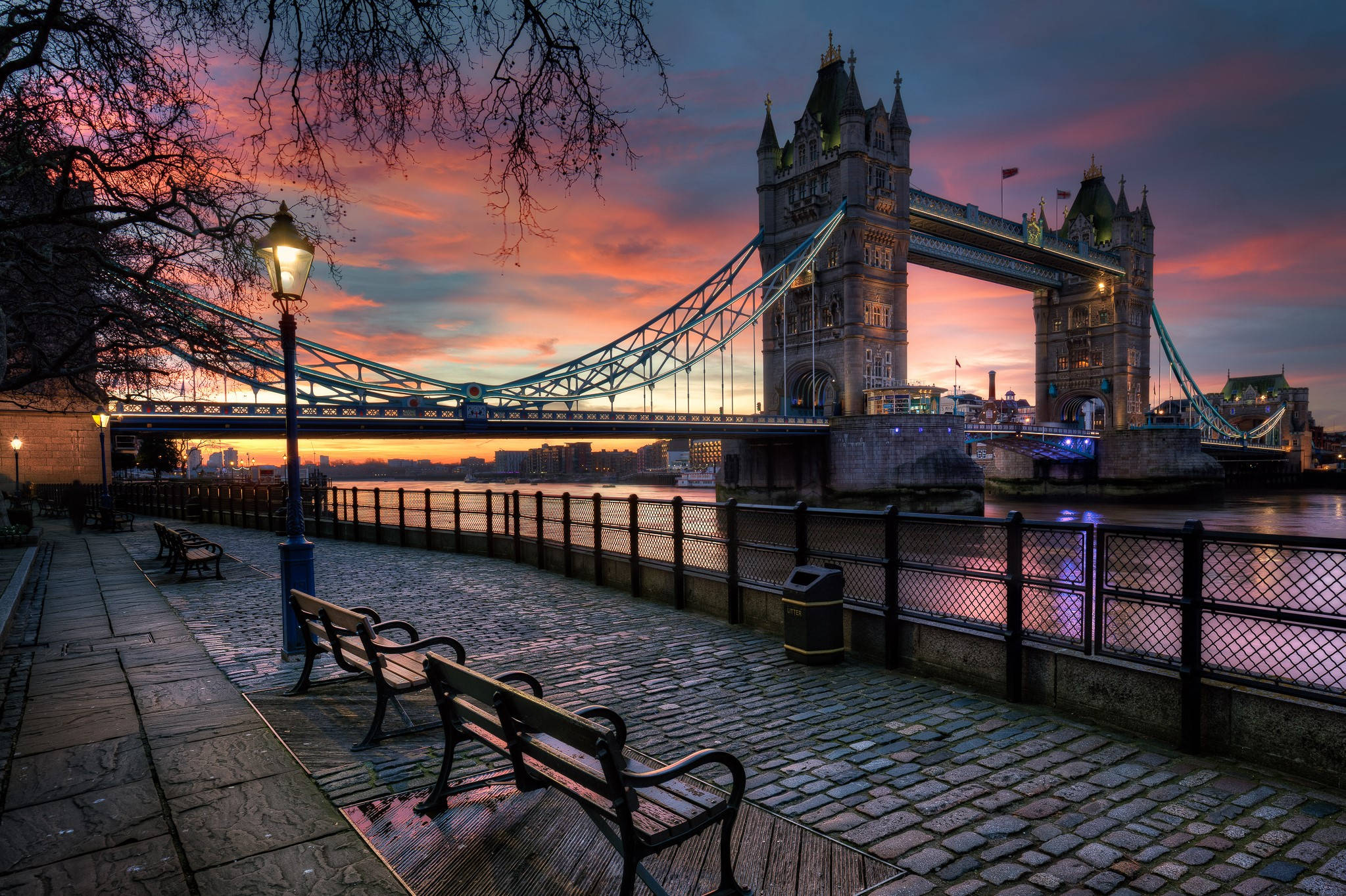 England 桌布 壁紙 — 倫敦塔橋在火紅的夕陽天空下閃耀，濕漉漉的鵝卵石反射著溫暖的光線，沿著泰晤士河畔步道。