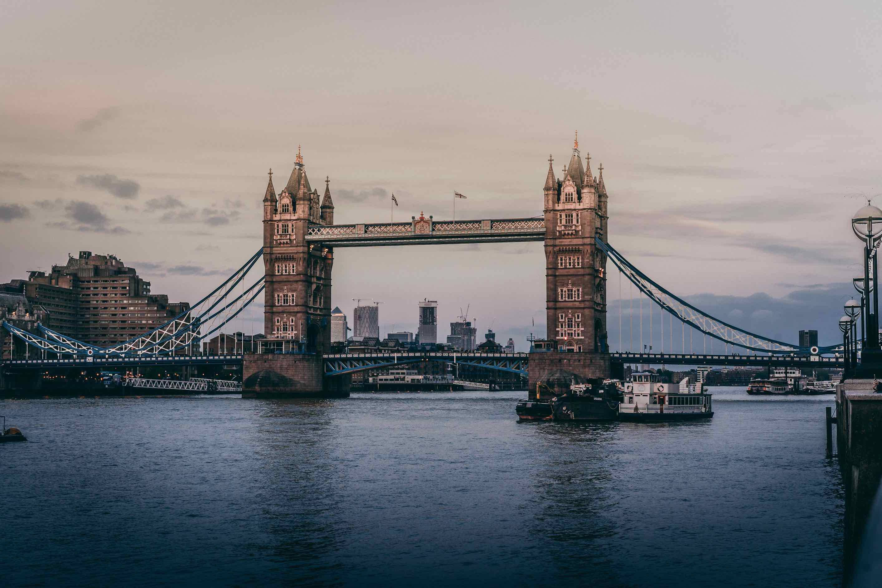 bridge 桌布 壁紙 — 倫敦塔橋在黃昏時分雄偉地橫跨泰晤士河，船隻在其標誌性塔樓下滑行。
