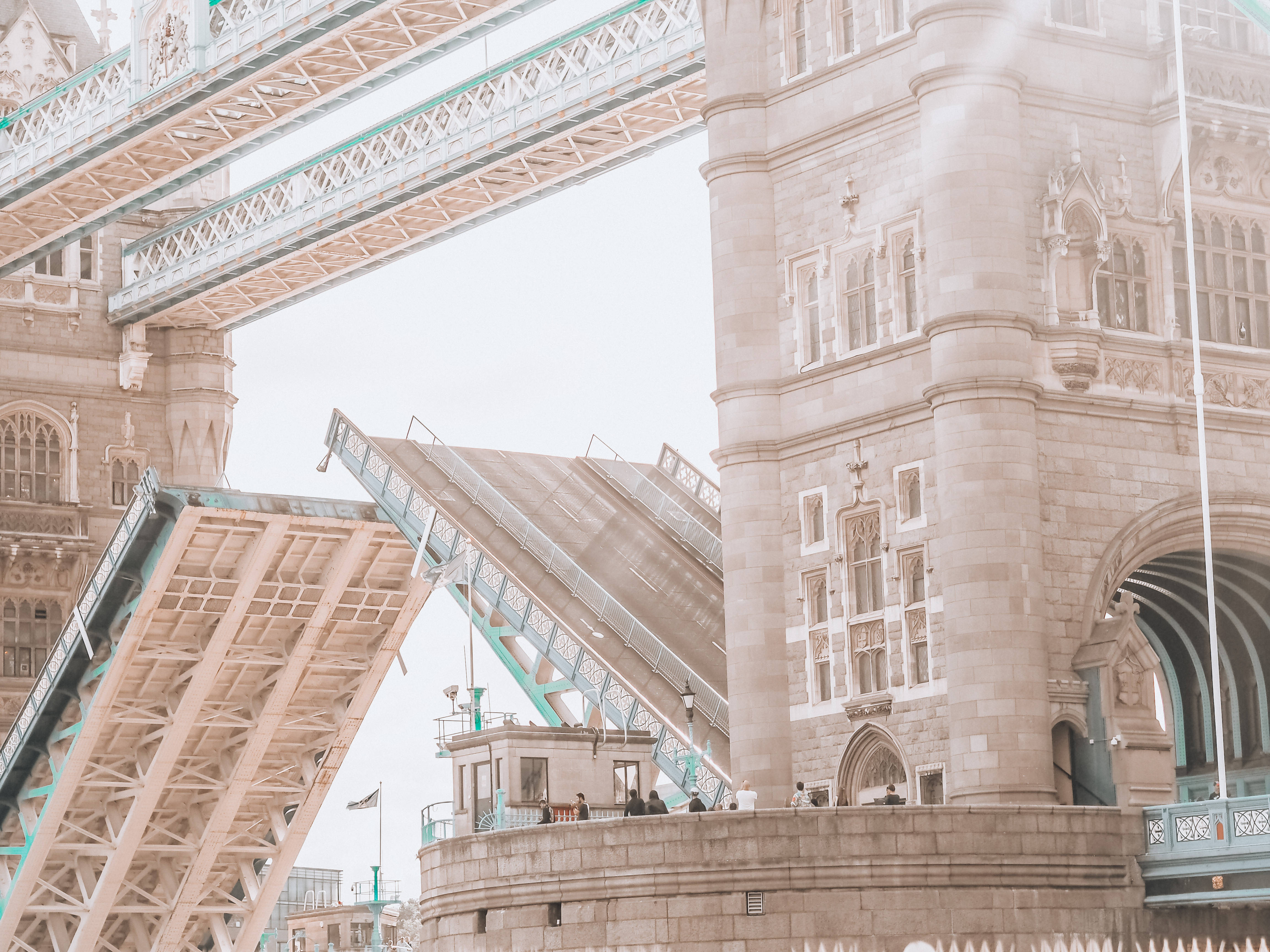 bridge 桌布 壁紙 — 倫敦塔橋的低角度視圖，其開合橋升起，襯托著柔和的多雲天空。
