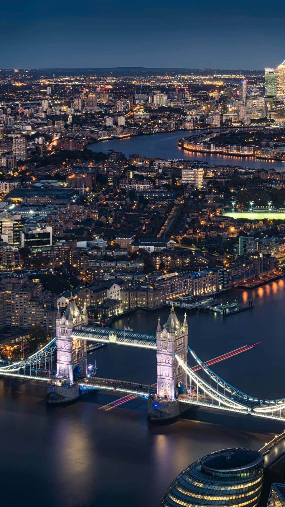 London iPhone 桌布 壁紙 — 倫敦塔橋的夜景鳥瞰圖，城市燈光倒映在泰晤士河上。