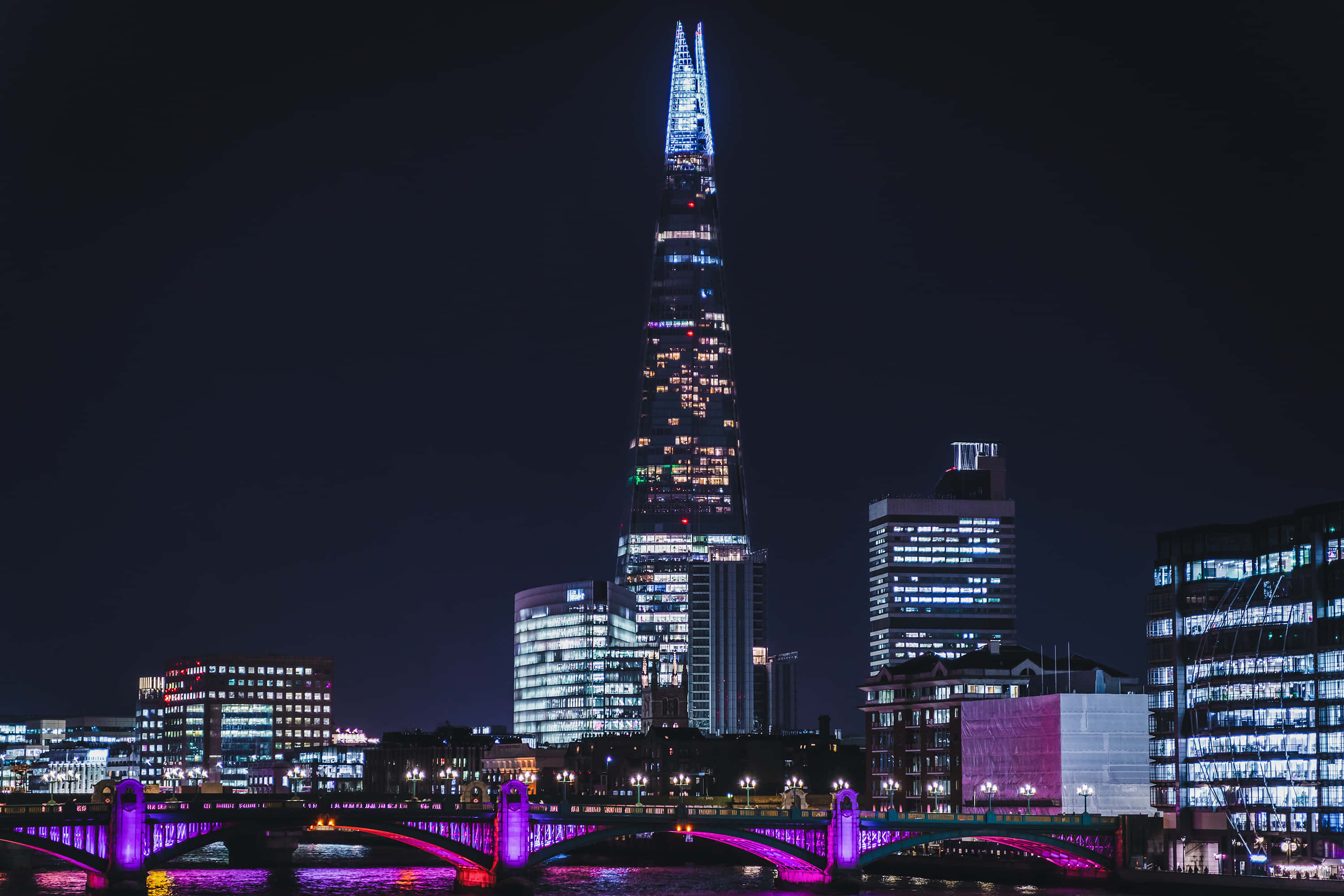 Night Aesthetic 桌布 壁紙 — 倫敦夜景天際線，碎片大廈發出藍光，河上有一座紫色燈光橋樑。