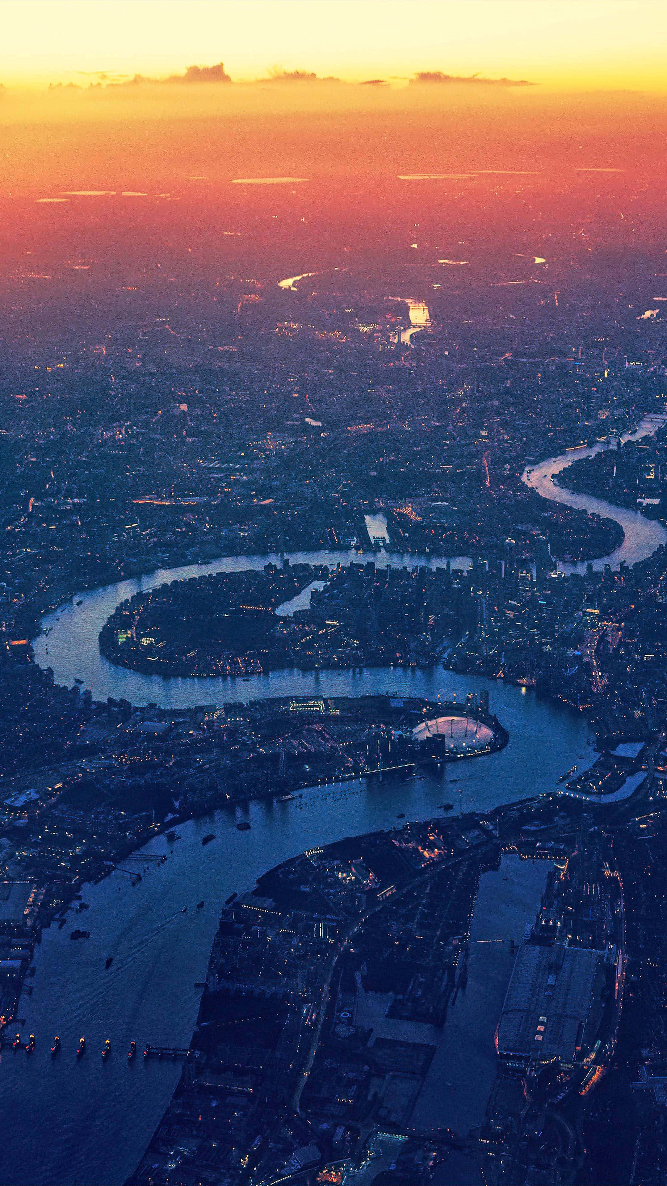 London iPhone 桌布 壁紙 — 倫敦日落時分的鳥瞰圖，泰晤士河蜿蜒穿過燈火輝煌的城市景觀。