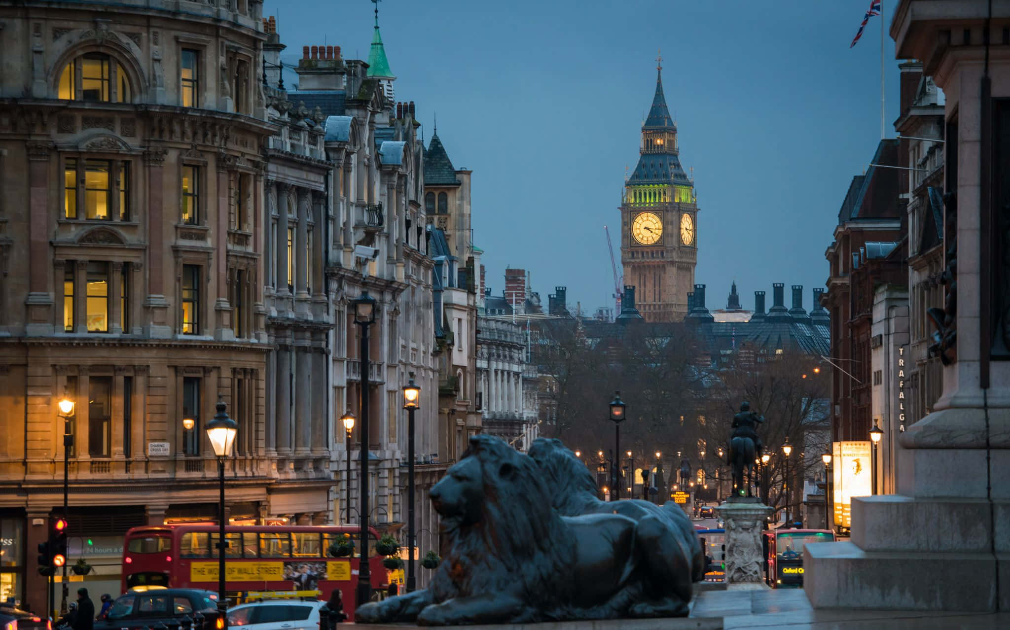 big ben 桌布 壁紙 — 倫敦標誌性大笨鐘和歷史建築的黃昏景色，前景有一座青銅獅子雕像。