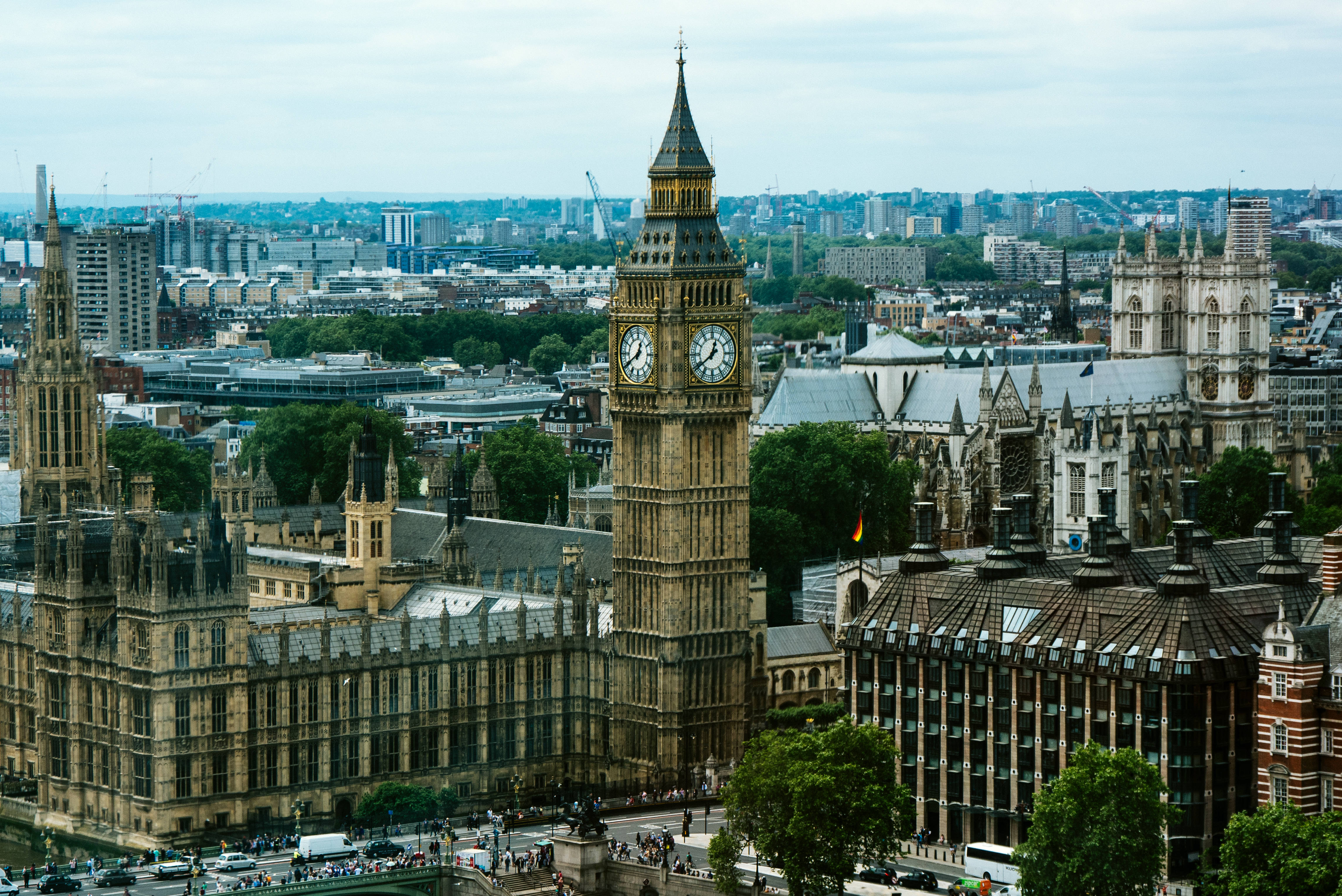 England 桌布 壁紙 — 倫敦標誌性大笨鐘鐘樓和國會大廈的鳥瞰圖，天空多雲，背景為城市景觀。
