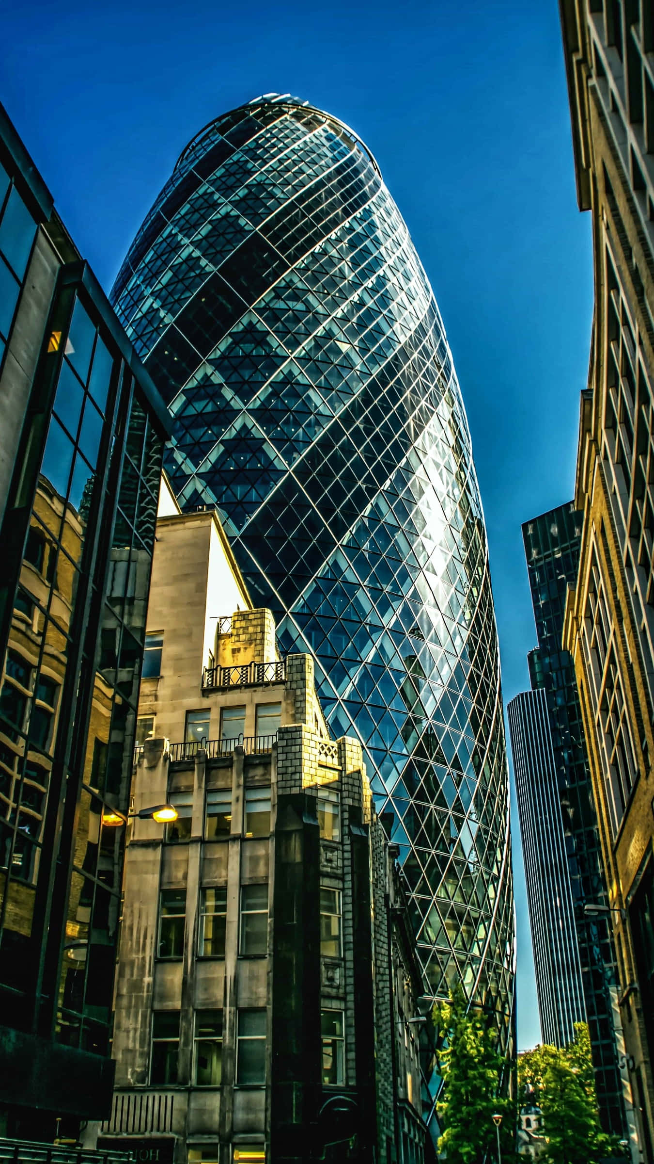 Skyscraper 桌布 壁紙 — 倫敦標誌性小黃瓜摩天大樓的低角度視角，其玻璃外牆反射著清澈的藍天。