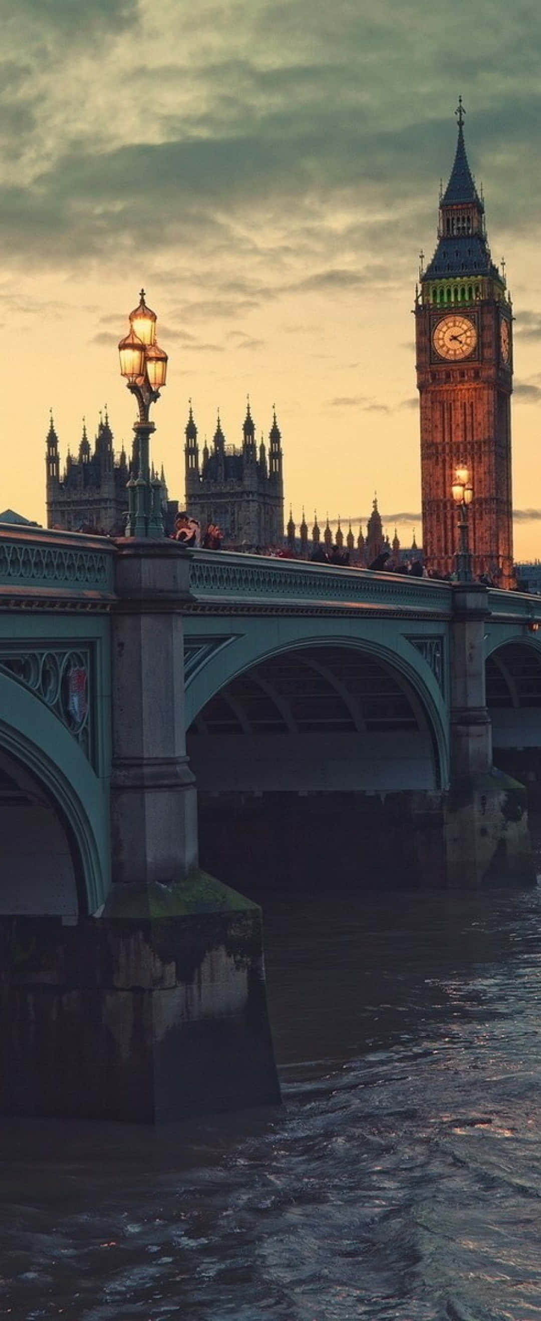 London iPhone 桌布 壁紙 — 倫敦標誌性的大笨鐘和西敏橋在暮色天空下溫暖地發光，泰晤士河在下方流淌。